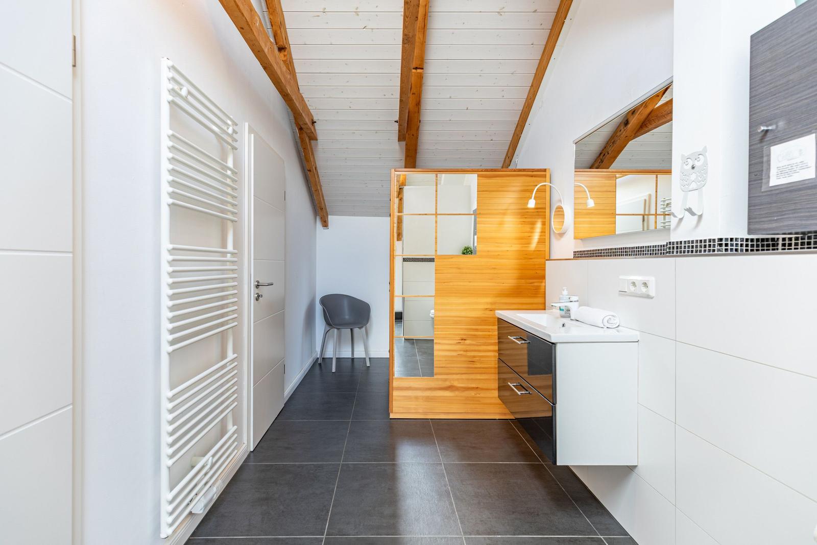 Badezimmer mit Holzumrandung, Waschbecken und Heizkörper an der Wand.