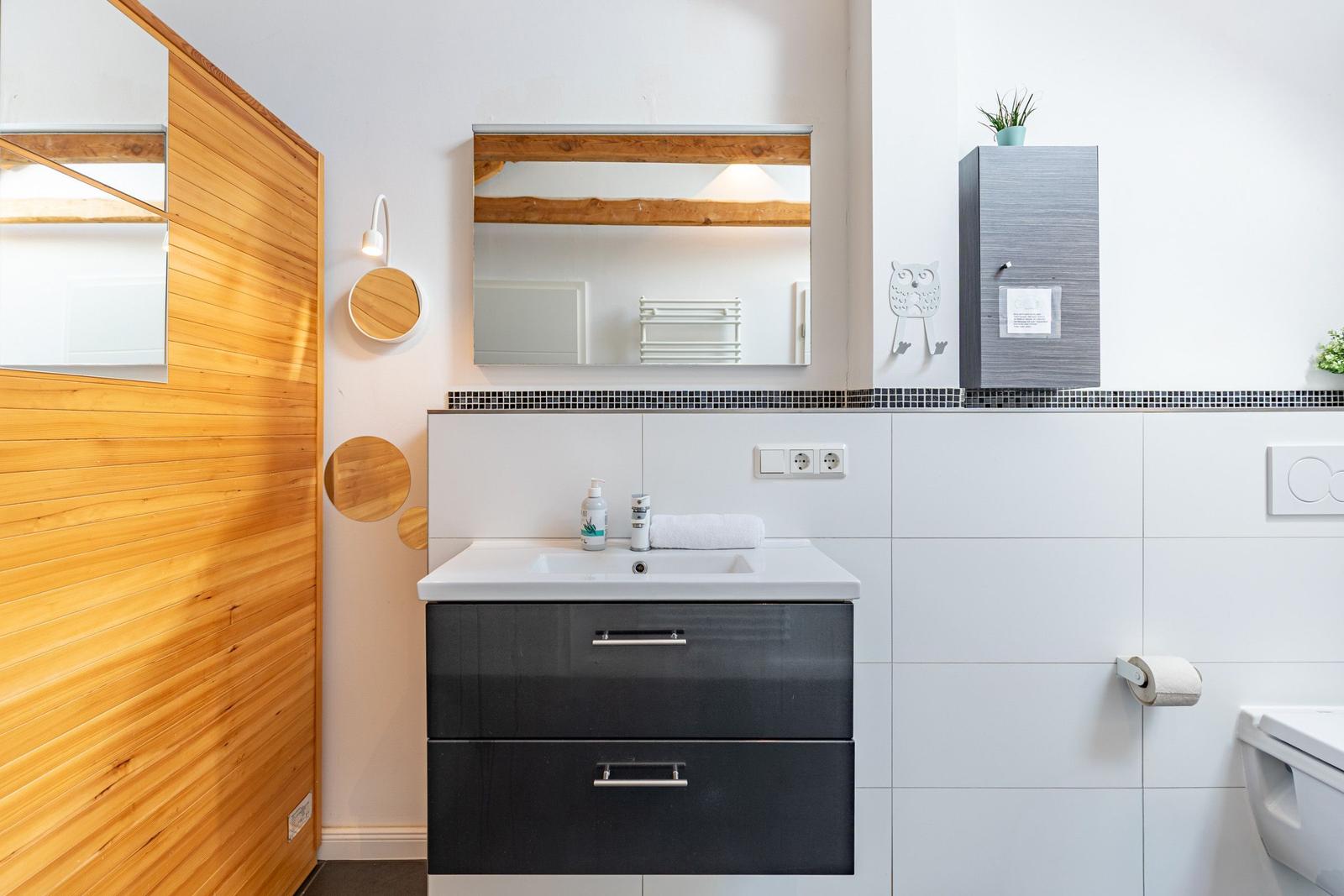 Badezimmer mit Waschbecken, Spiegel und Holzwand
