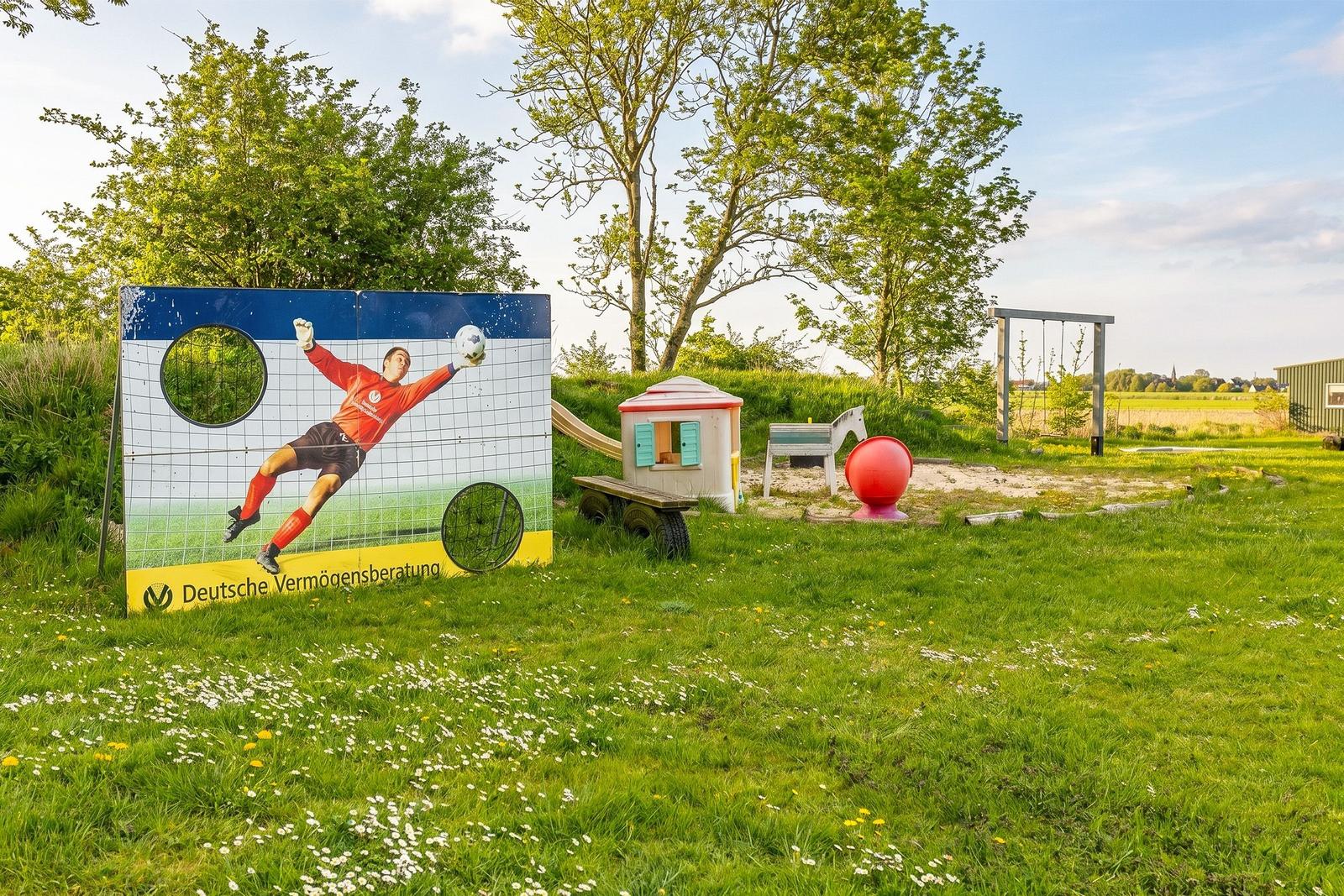 Grüner Garten mit Kinderspielplatz und Torwandschild.