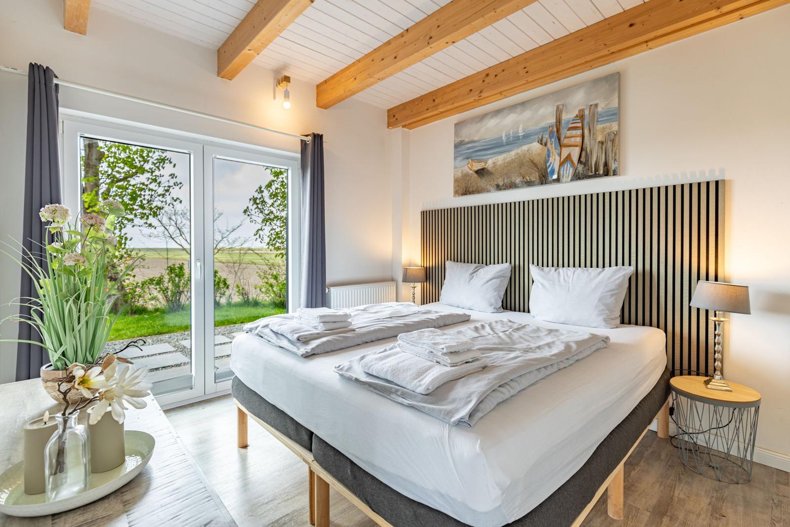 Schlafzimmer mit Doppelbett, Holzbalkendecke und Blick auf Garten