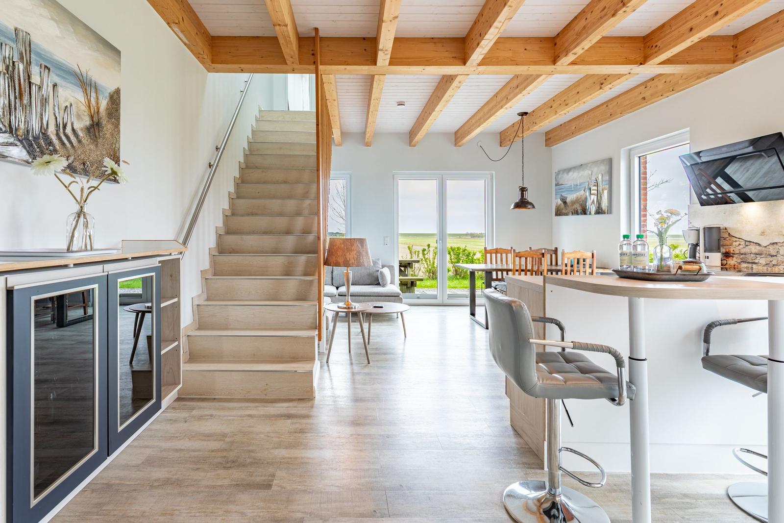 Haus mit offener Küche, Holzdecke und Treppe zur oberen Etage.