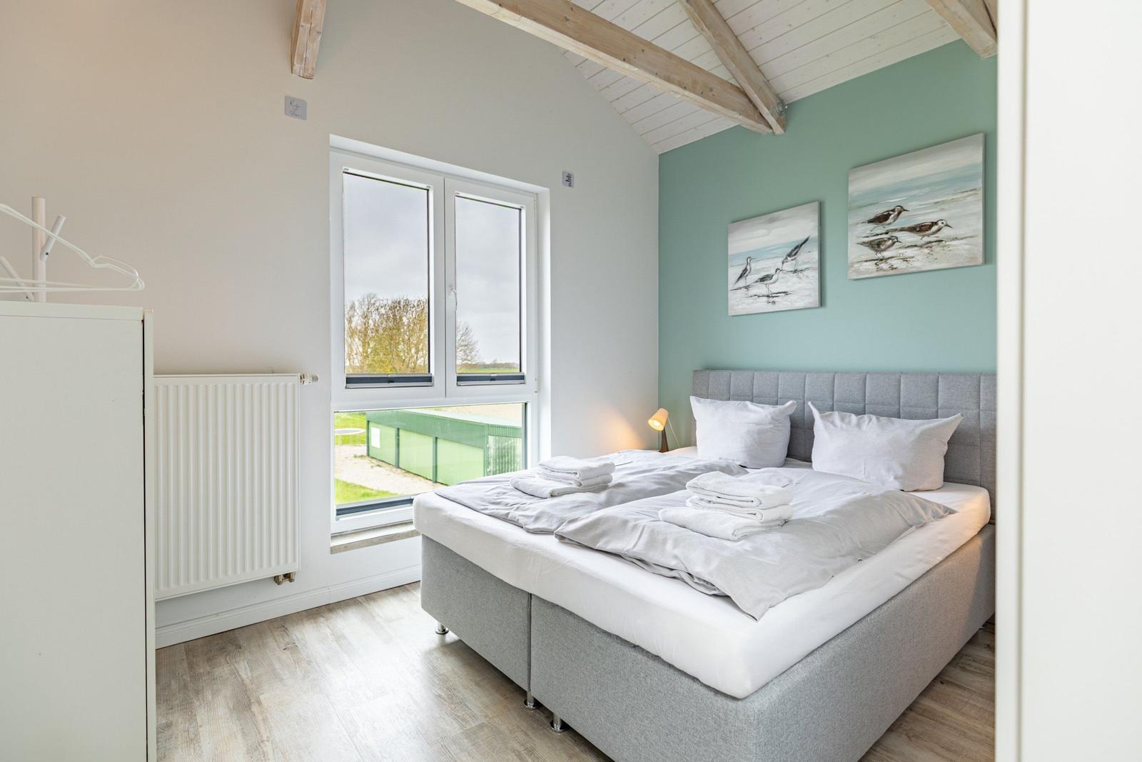 Schlafzimmer mit Doppelbett, Fenster und Wandbildern