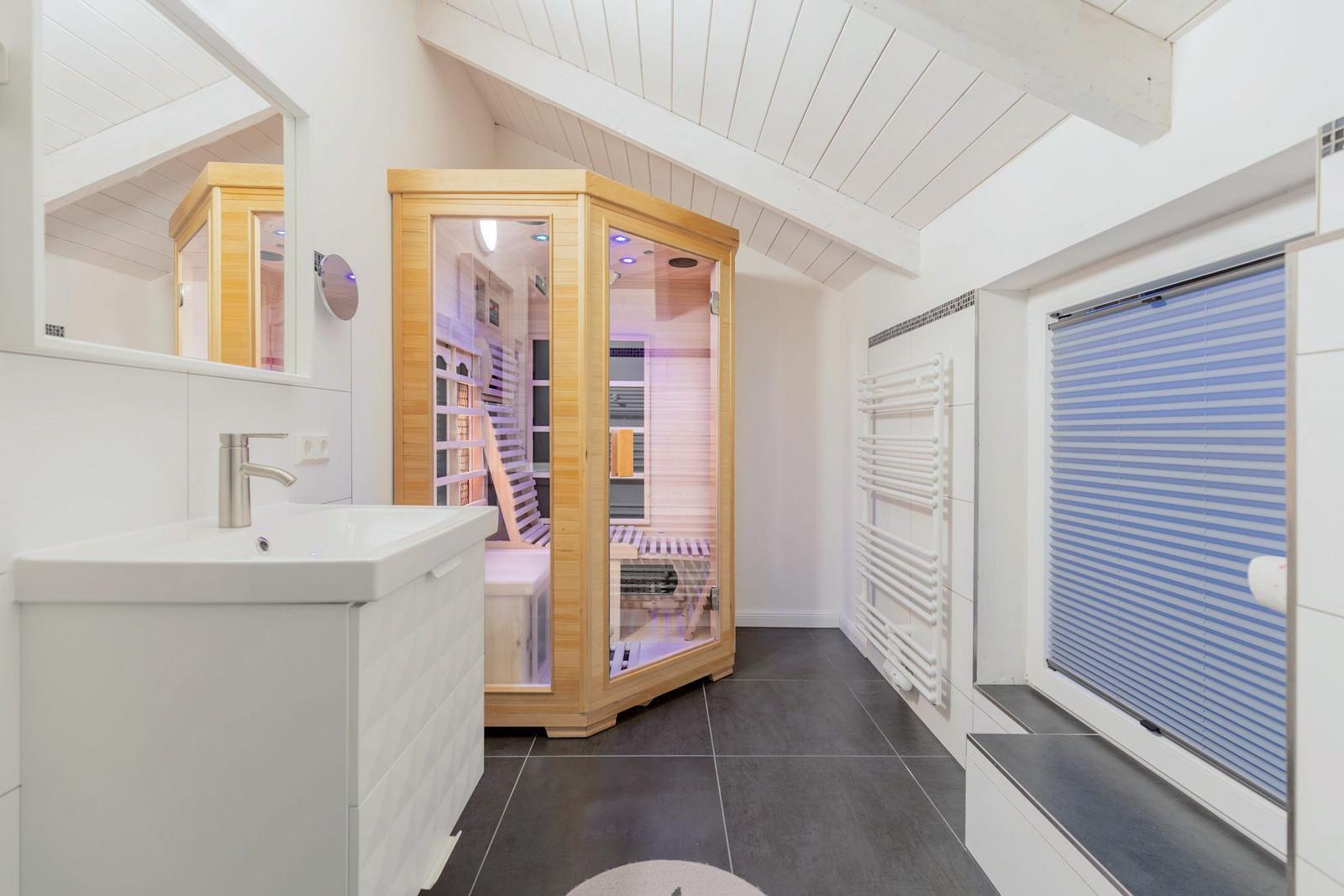 Dusche mit Sauna, Waschbecken und Heizkörper an der Wand.