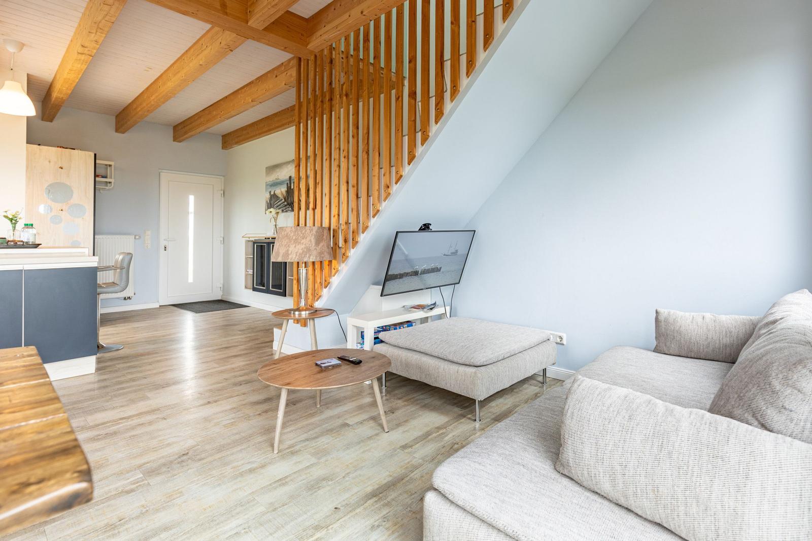 Wohnzimmer mit Sofa, Fernseher und Holzstufenhaus unter Dachschrägen.