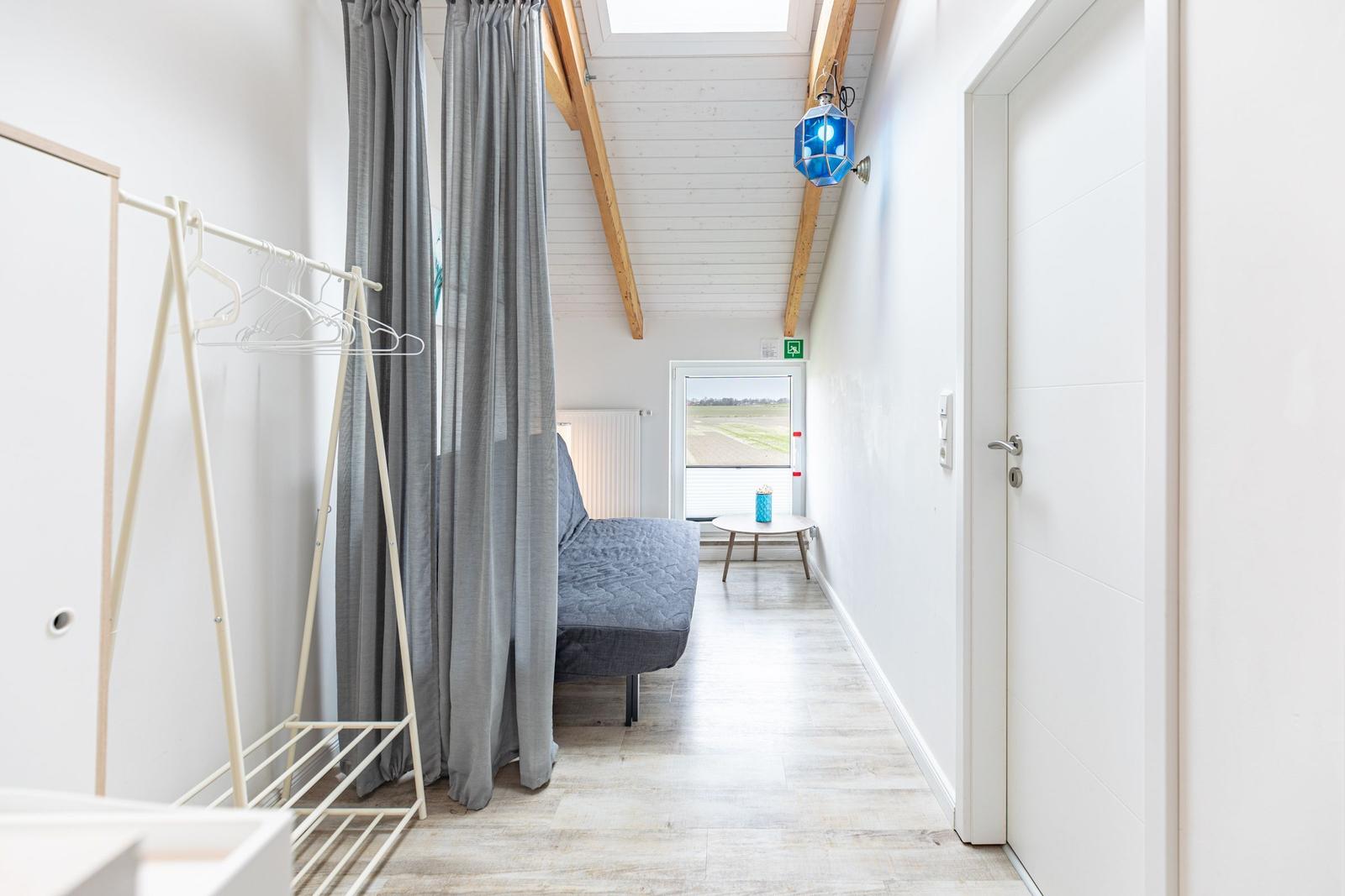 Schlafzimmer mit Bett, Garderobe und Fensterblick auf Felder.