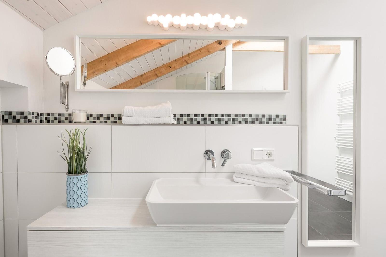 Bad mit Waschtisch, Spiegel und Dusche unter Holzdecke