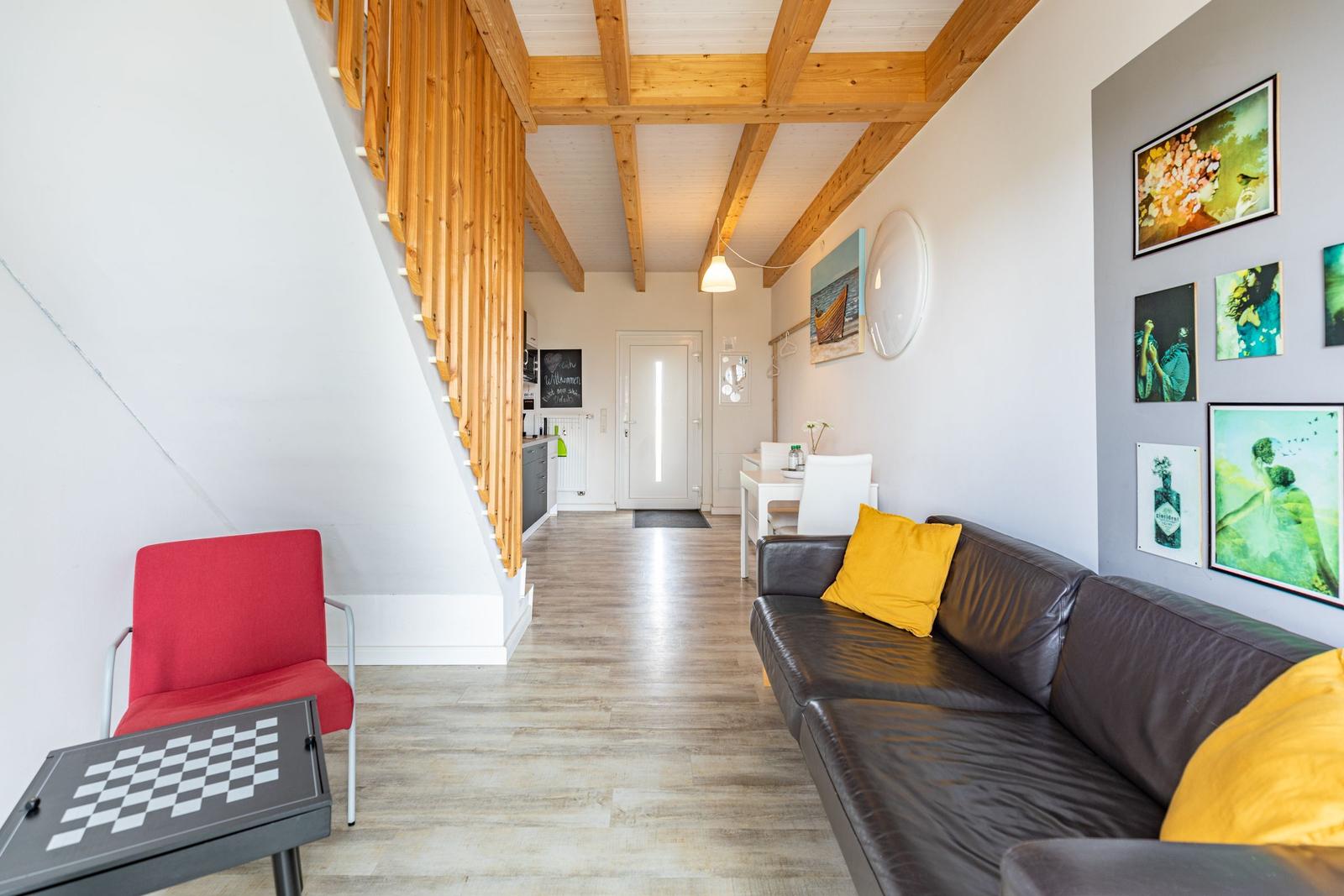 Wohnraum mit Sofa, roter Sitzgelegenheit und Holzbalkendecke.