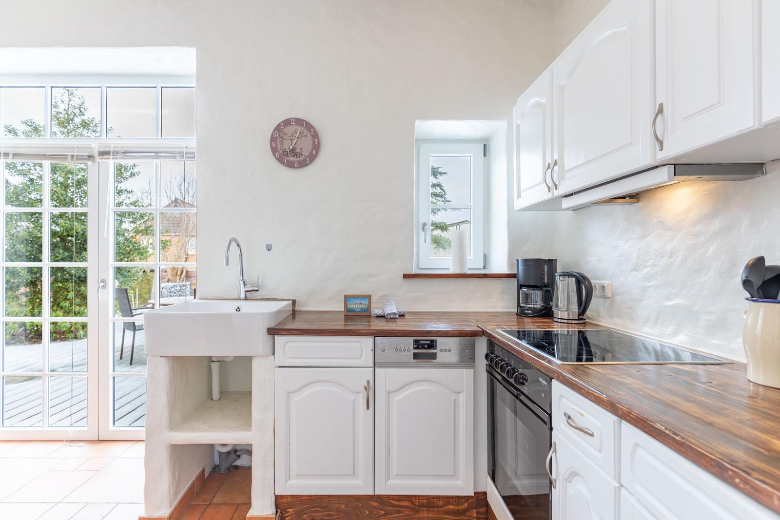 Kitchen with white cabinets, wooden countertops, and view to the terrace.
