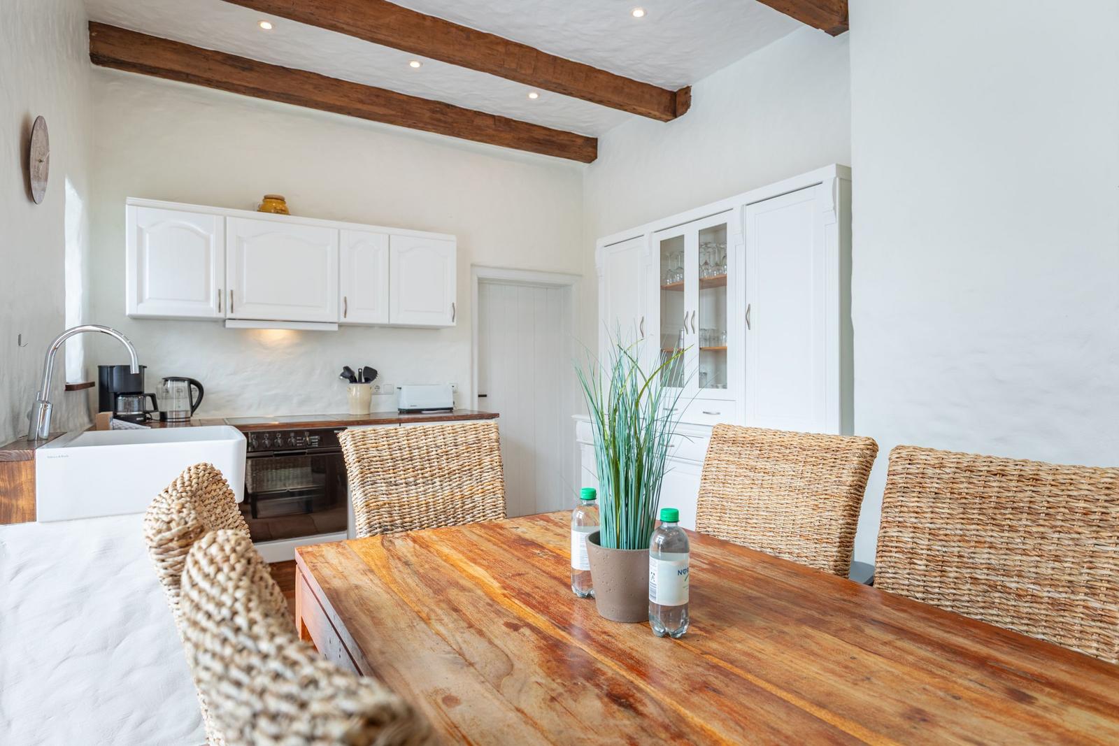 Kitchen with dining area, white cabinets, and rustic wooden table with chairs.