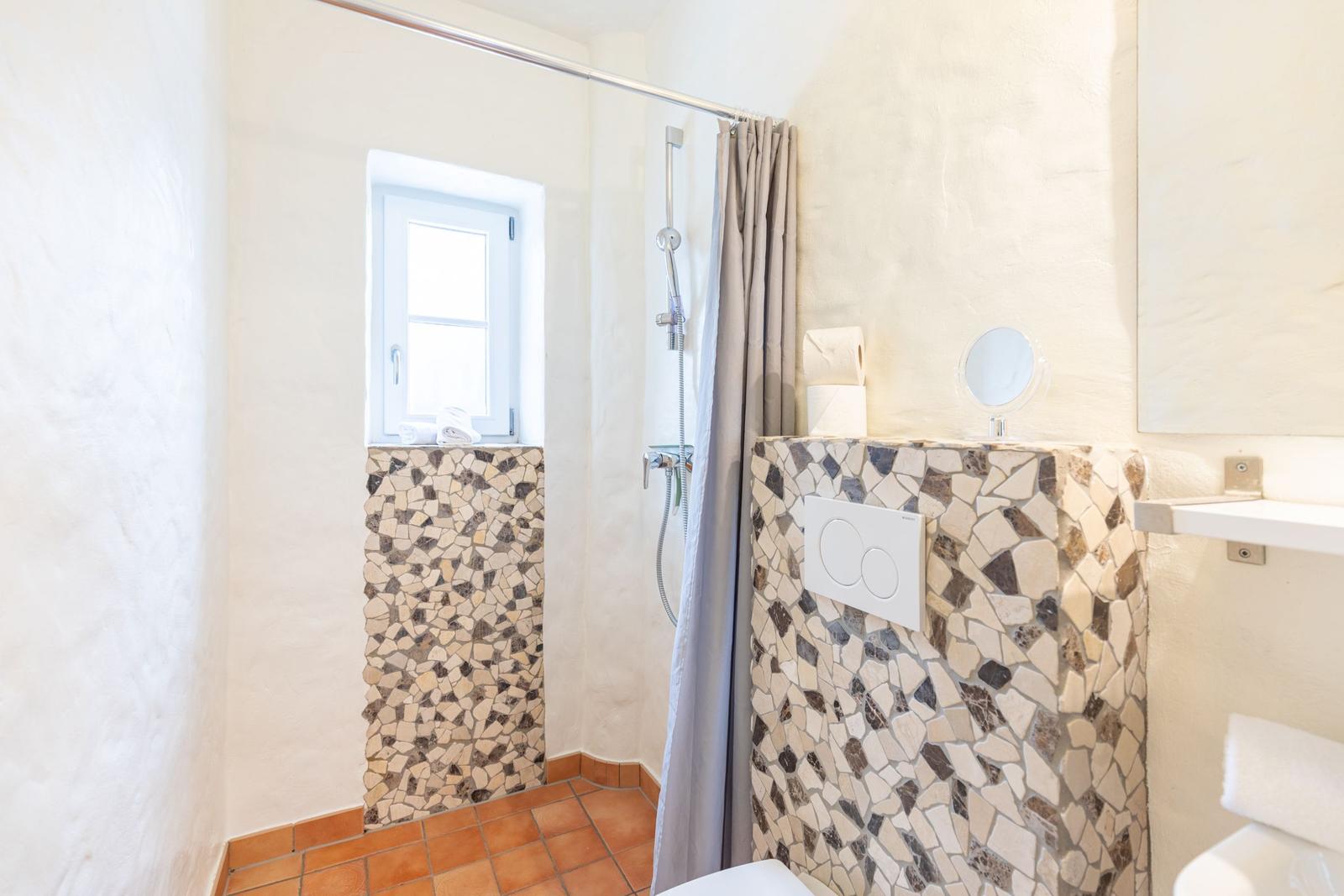 Bathroom with shower, mosaic wall, and window