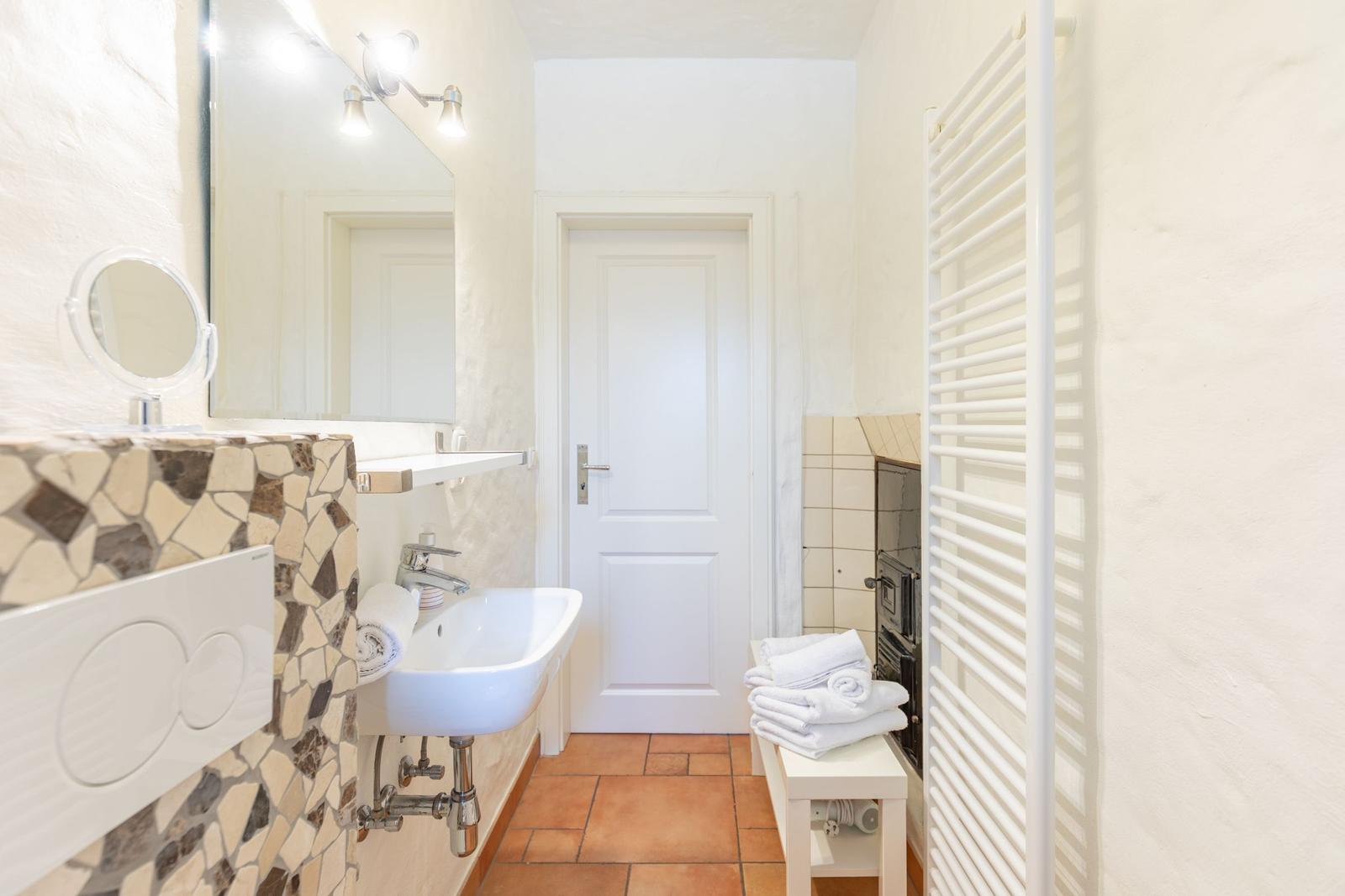Bathroom with sink, mirror, towel rack, and heater.