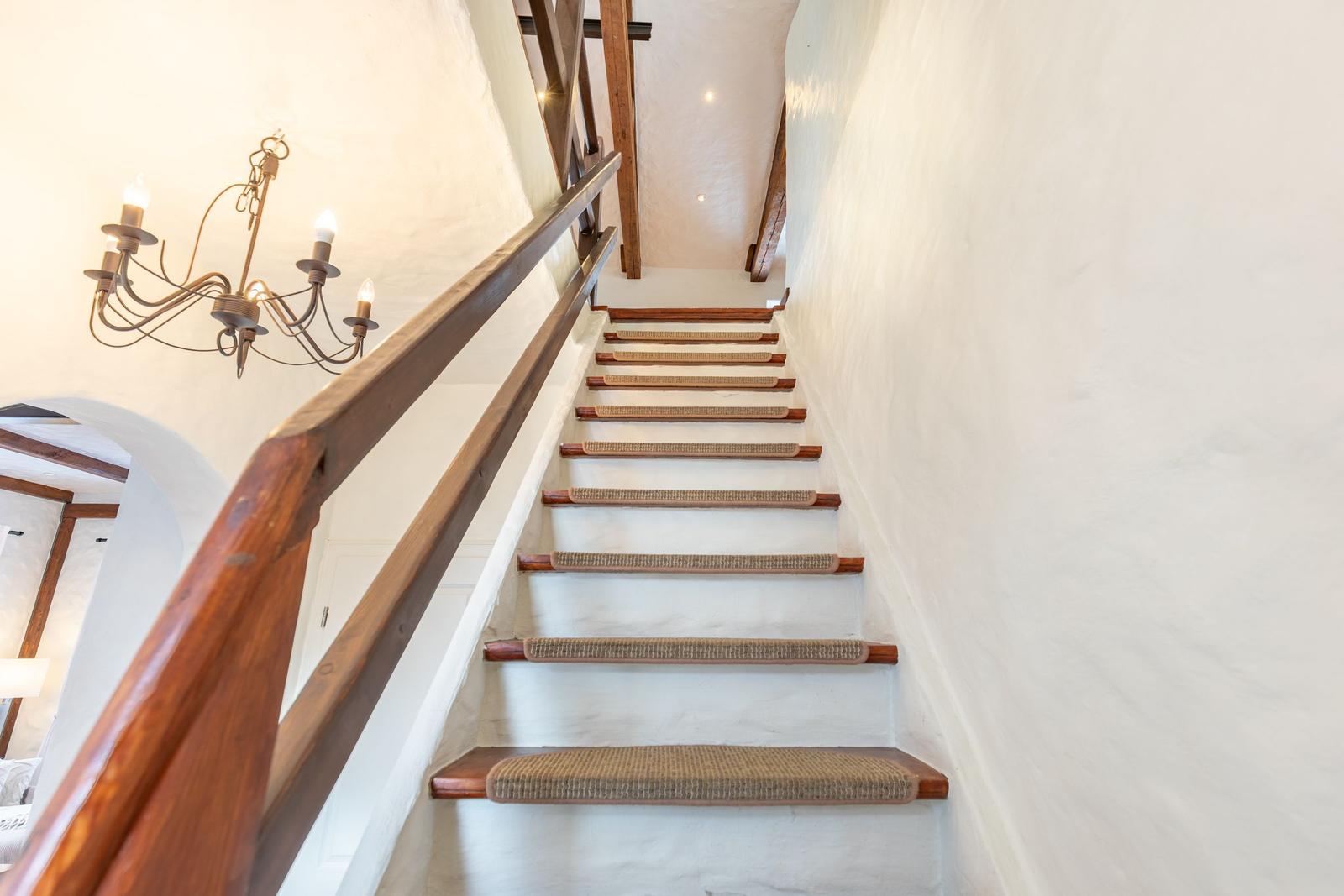 Wooden staircase with rope mat leads upward. A lantern hangs on the wall.