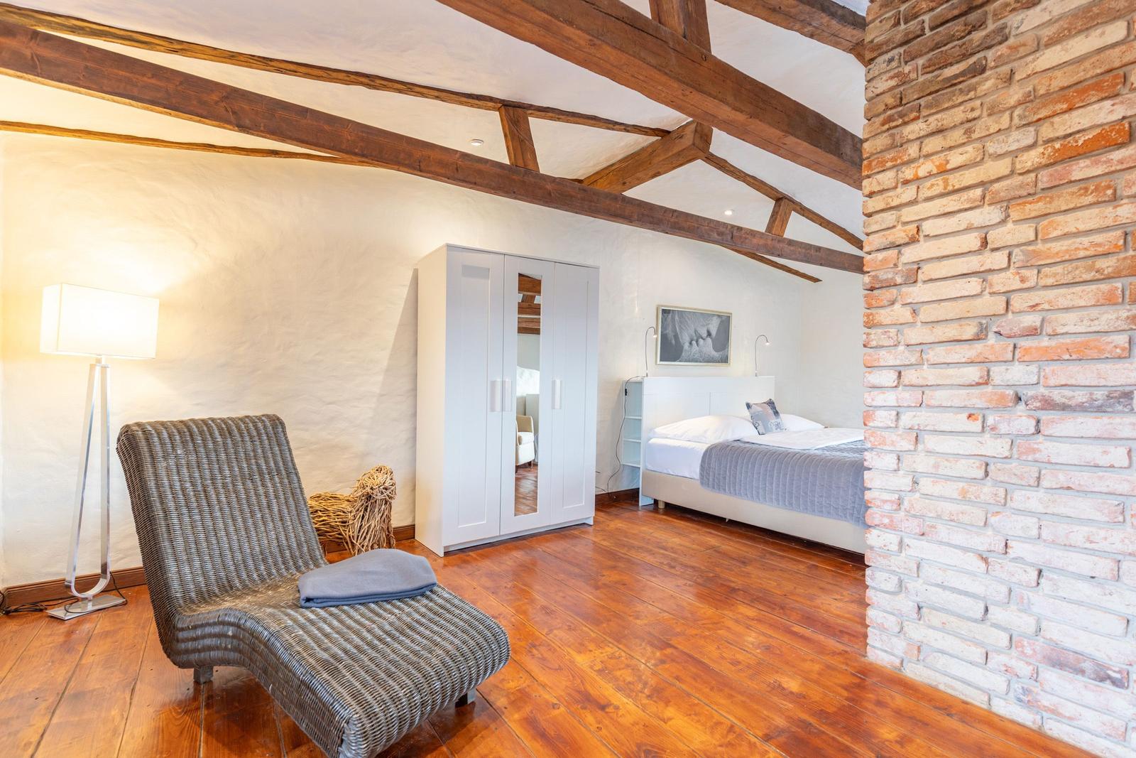 Bedroom with wooden floor, pillows, bed, and wardrobe.