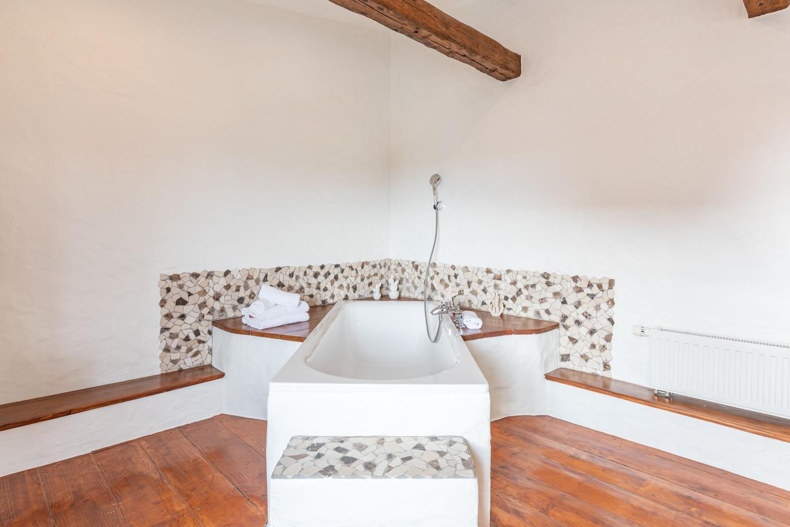 Bathroom with bathtub, mosaic tiles, and wooden floor