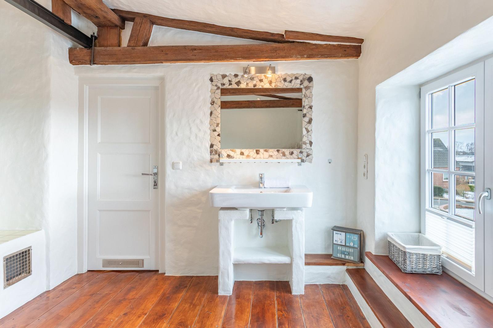 Bathroom with sink, mirror with mosaic frame, and window with seat bench.