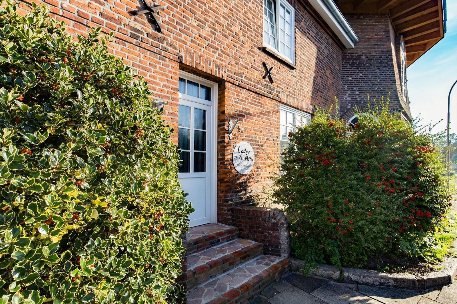 Entrance of a brick house with white doors and plants