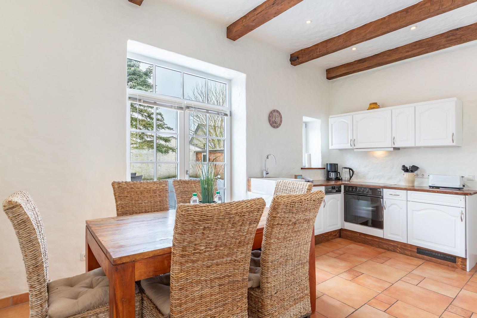 Kitchen with dining area, white cabinets, and wooden beams on the ceiling.
