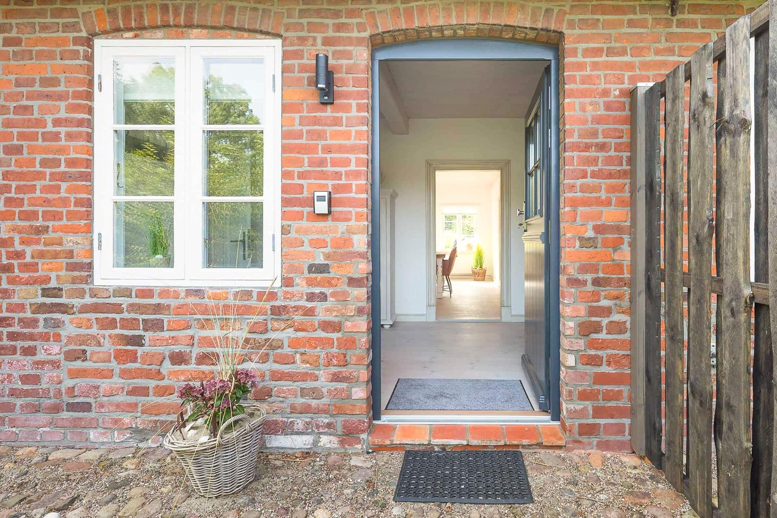 Entrance with red brick house, door, and window. View inside.