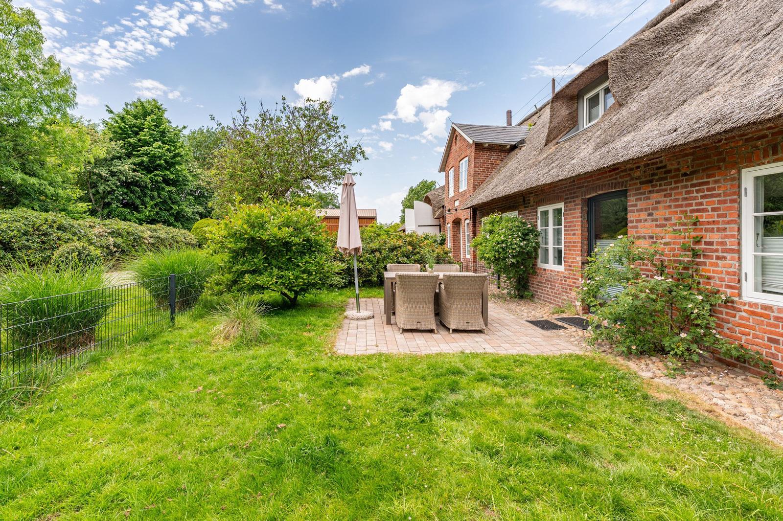 Rear yard with patio, garden, and thatched house.