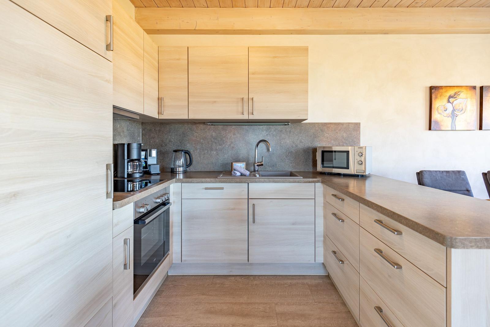 Modern kitchen with wooden cabinets, sink, and microwave.