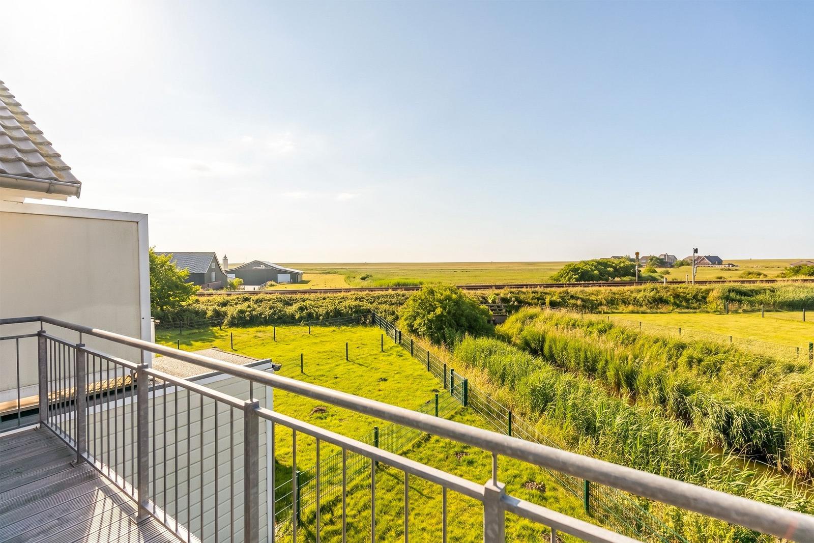 Balcony with view of green meadows and tracks