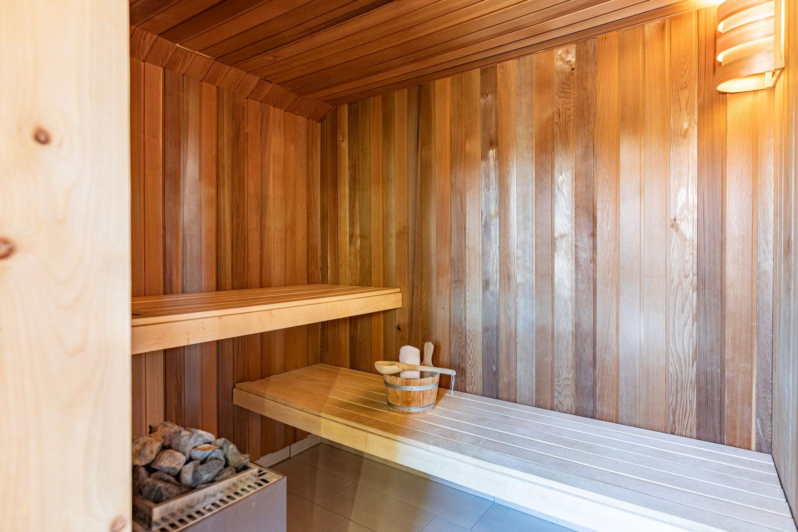 Sauna with wooden walls, seating bench, and stone tray