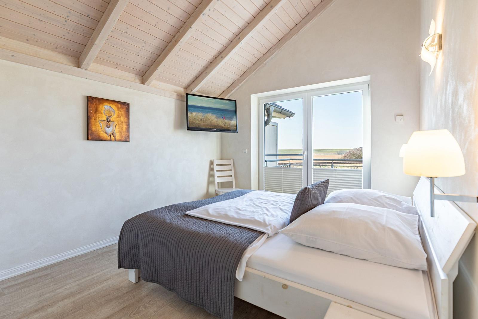 Bedroom with bed, TV, and balcony view.