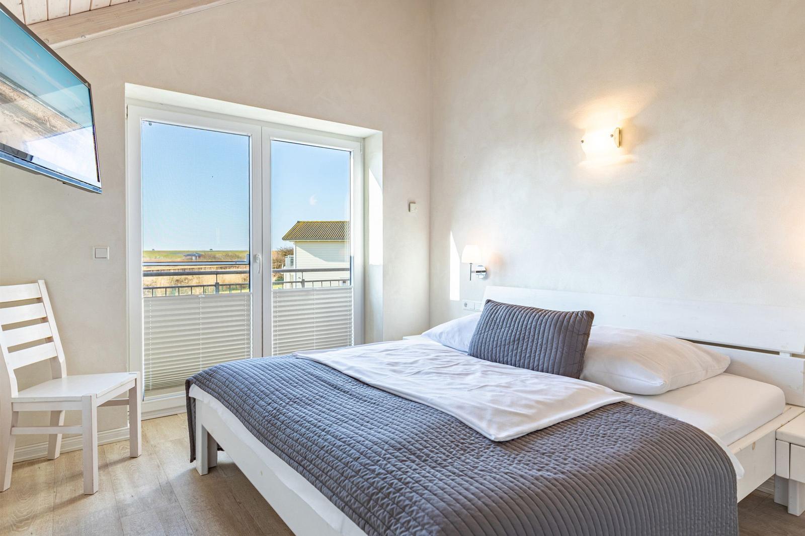 Bedroom with bed, TV, and balcony view.