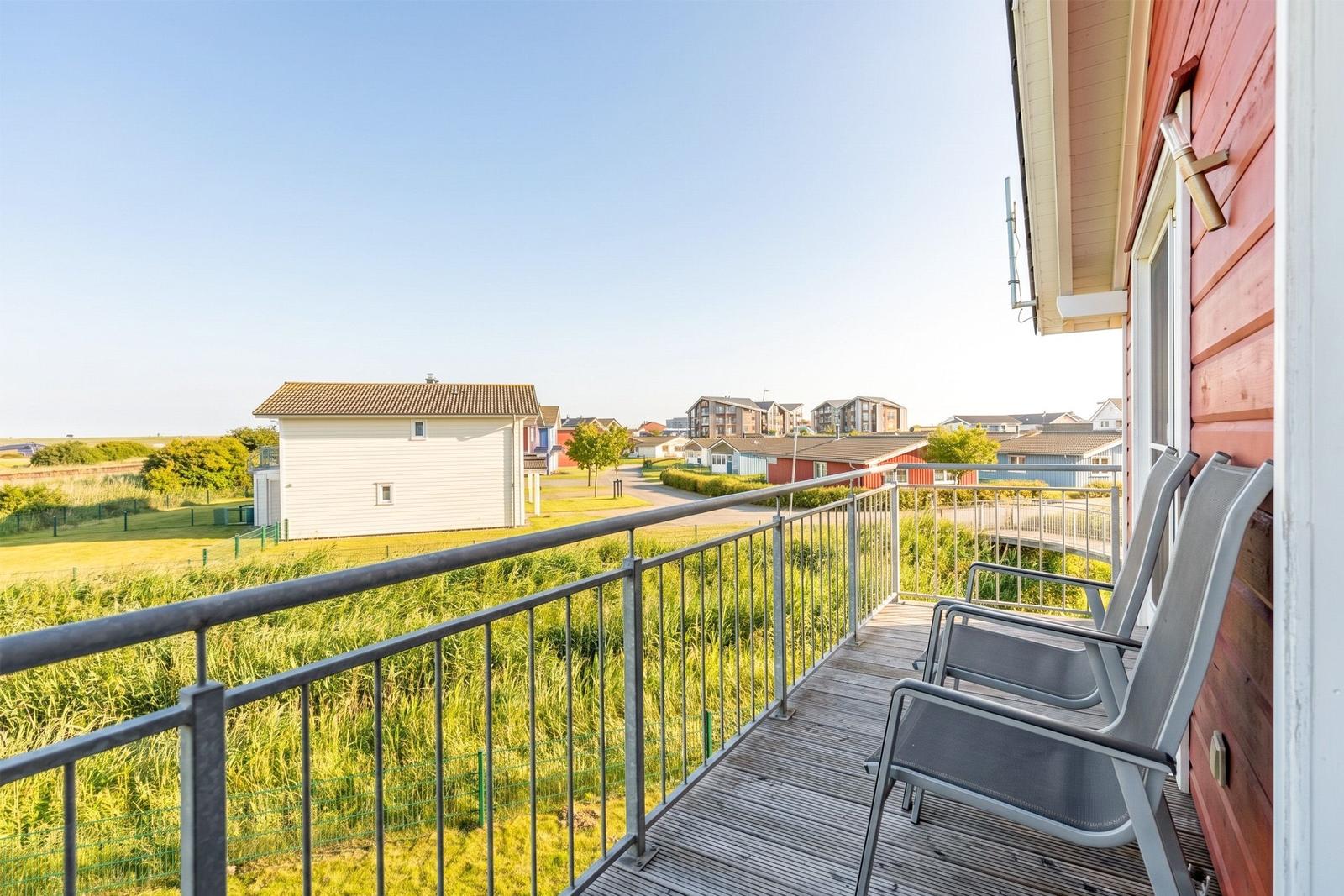 Terrace with seating and view of houses and green areas.