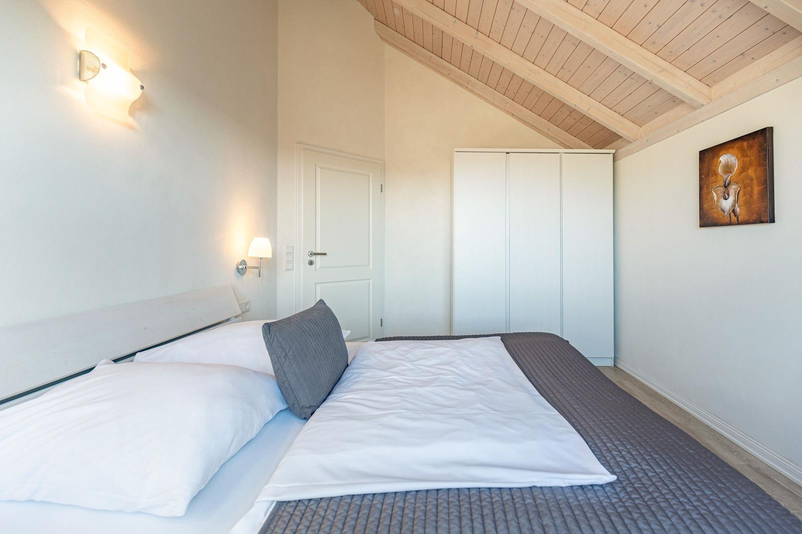 Bedroom with bed, wardrobe, and wooden ceiling.