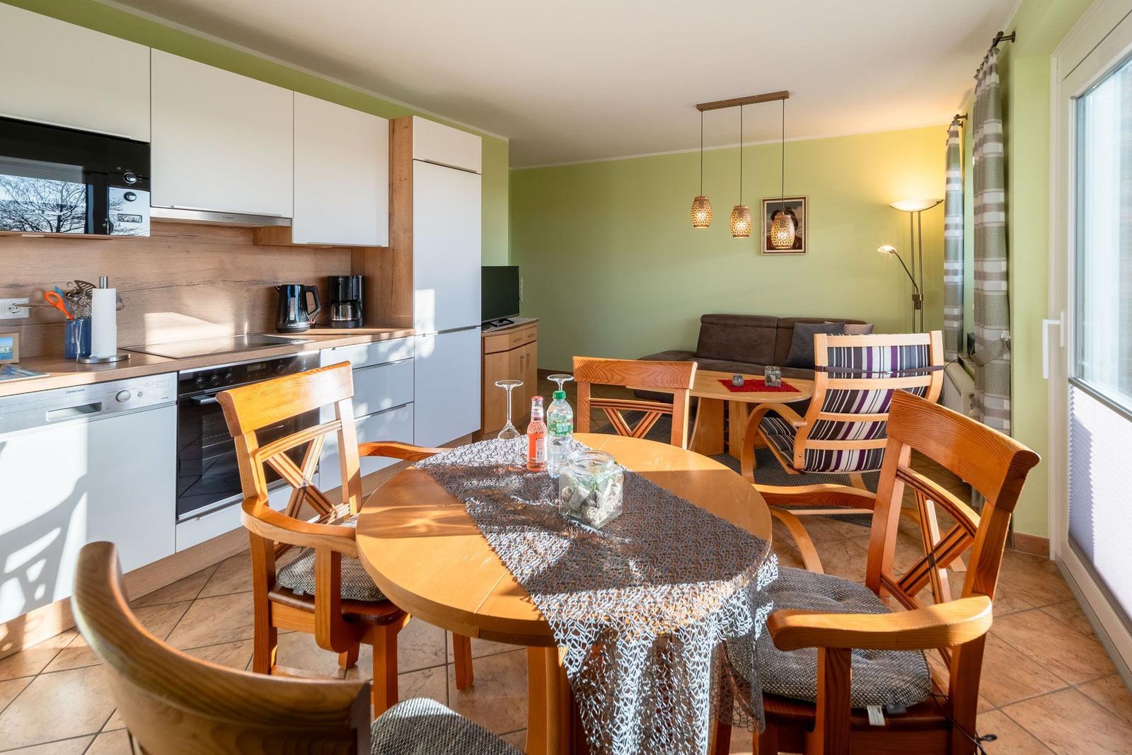 Küche mit Essbereich und Wohnzimmer mit Sofa und Holztisch.