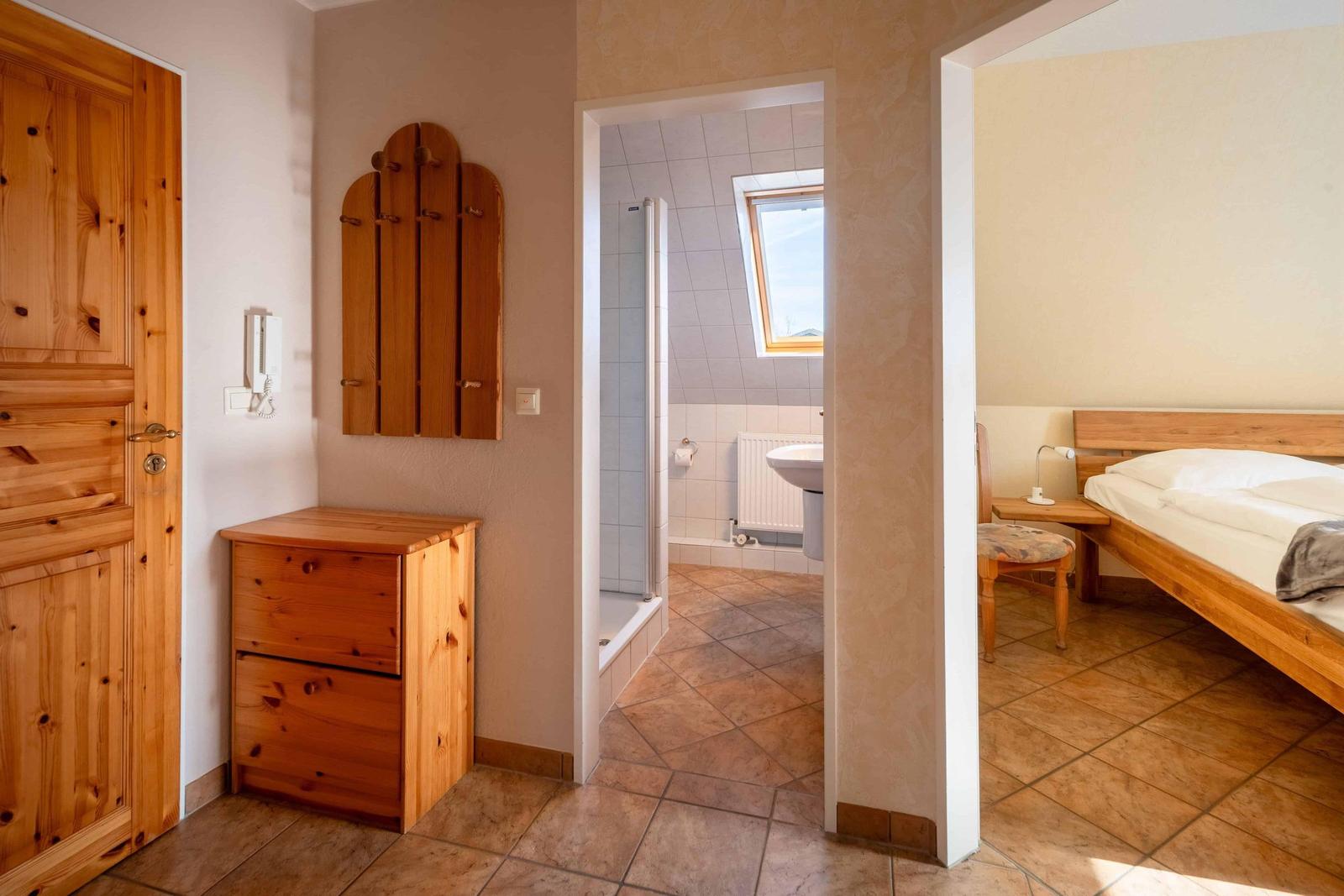 Schlafzimmer mit Holzbett, Bad mit Dusche und Fenster, Holzmöbel und Tür