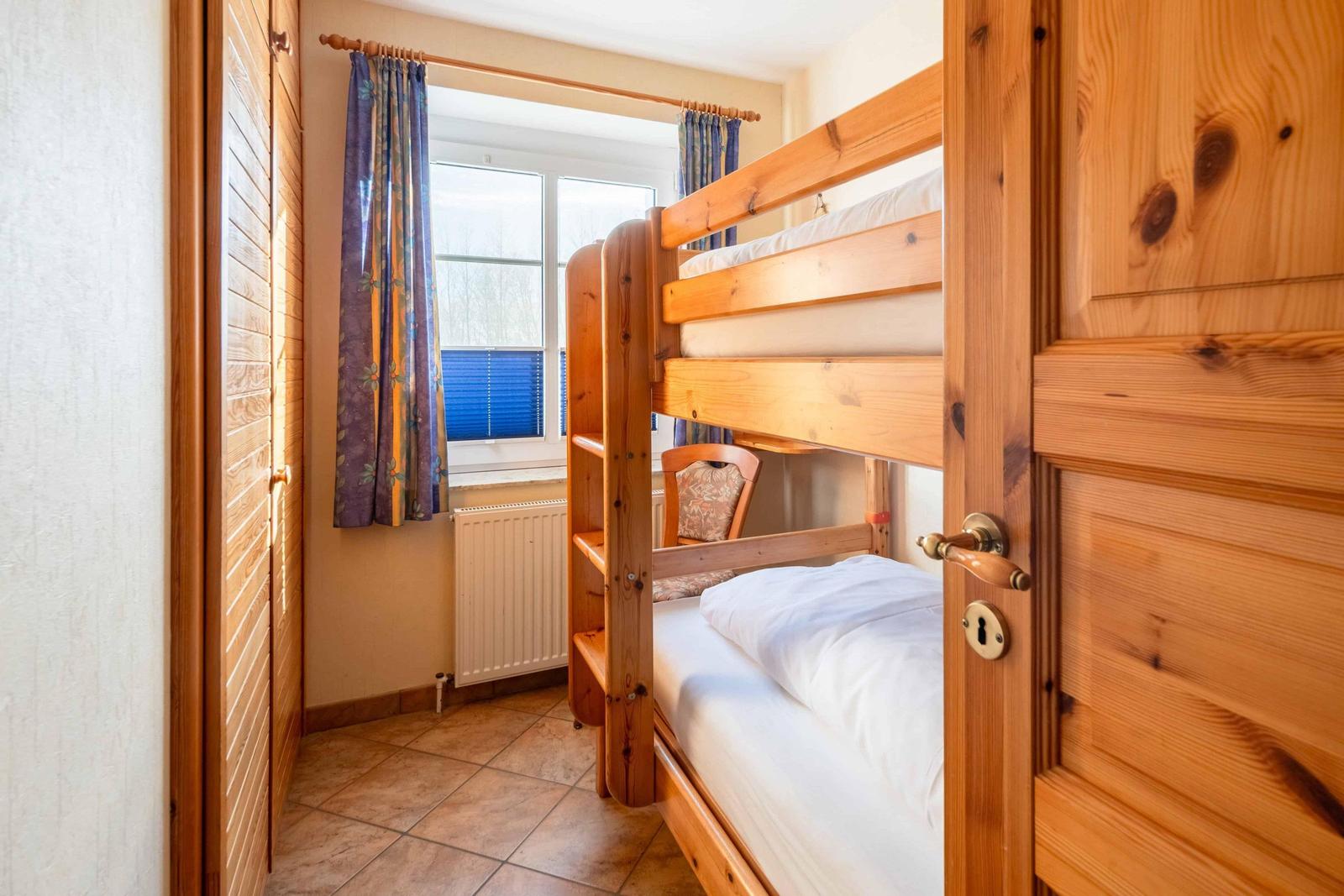 Ein Schlafzimmer mit Holz-Etagenbett, Fenster und Heizung.