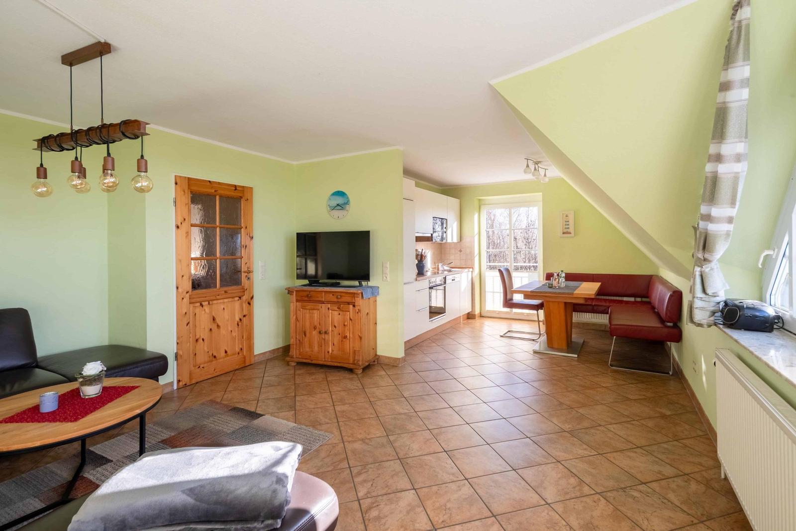 Wohnbereich mit Küche, Essplatz und TV. Holztüren und -möbel. Dachschrägen und Fenster.