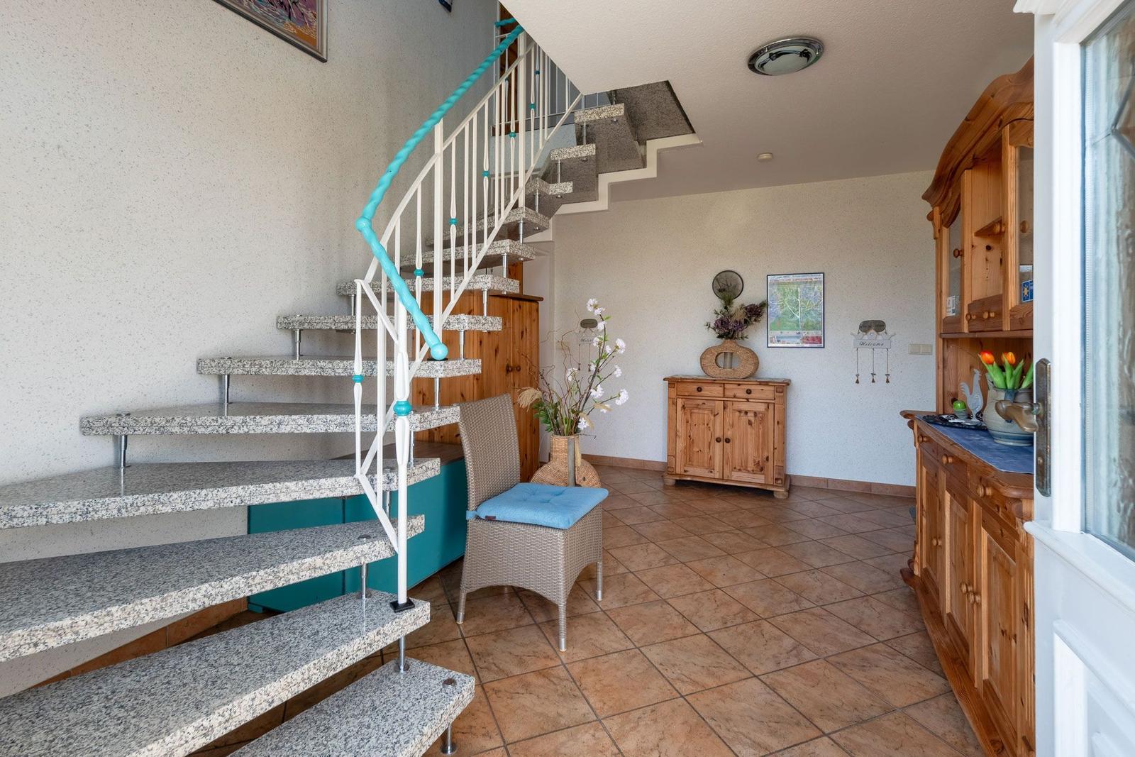 Staircase with spiral stairs and wooden furniture in the hallway.