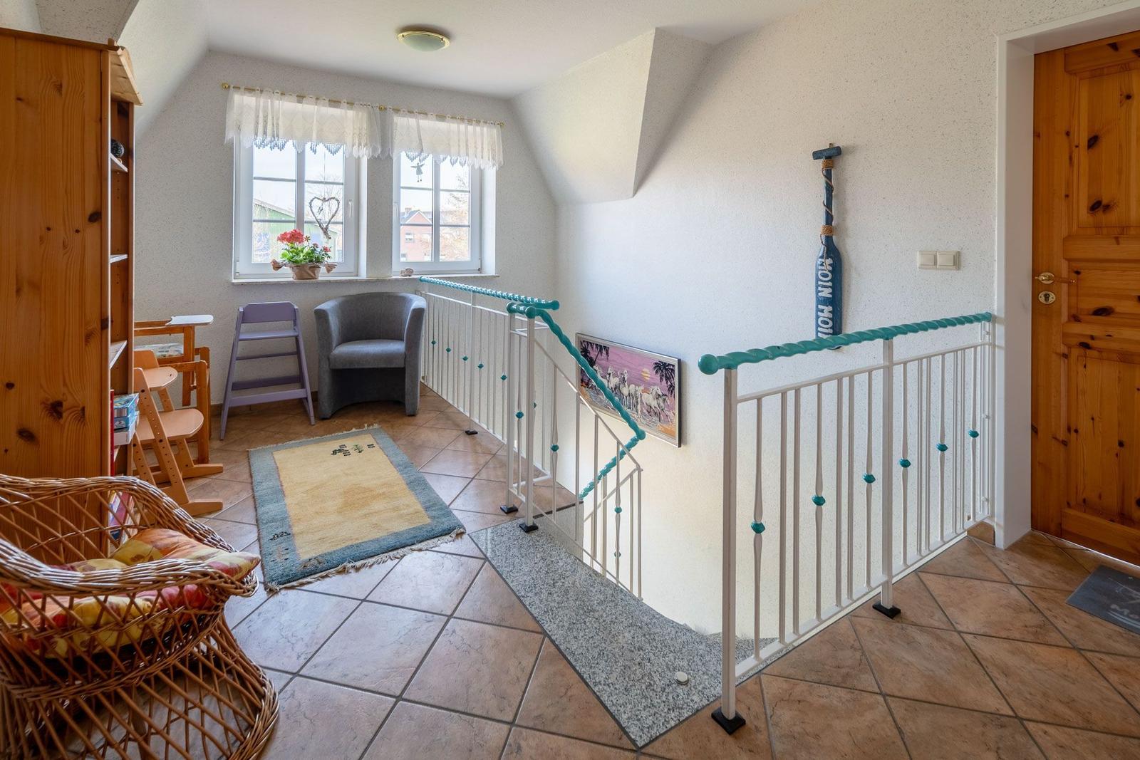 Eingangsbereich mit Treppe, Holztüren und Sitzgelegenheiten.