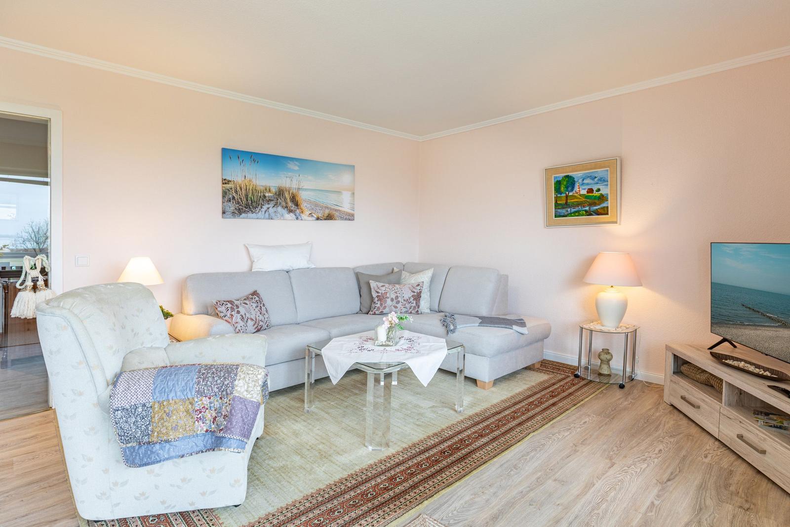 Wohnzimmer mit Sofa, Sessel, Couchtisch und Fernseher.