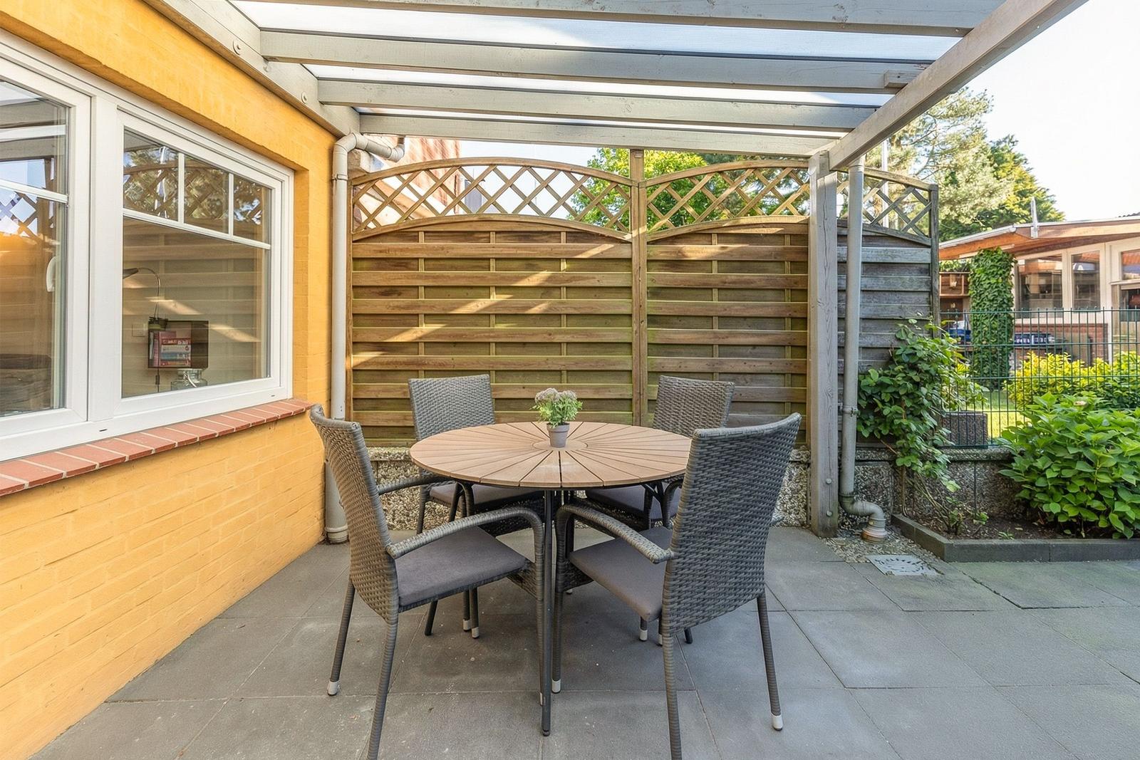 Terrasse mit Tisch und vier Stühlen unter Dach