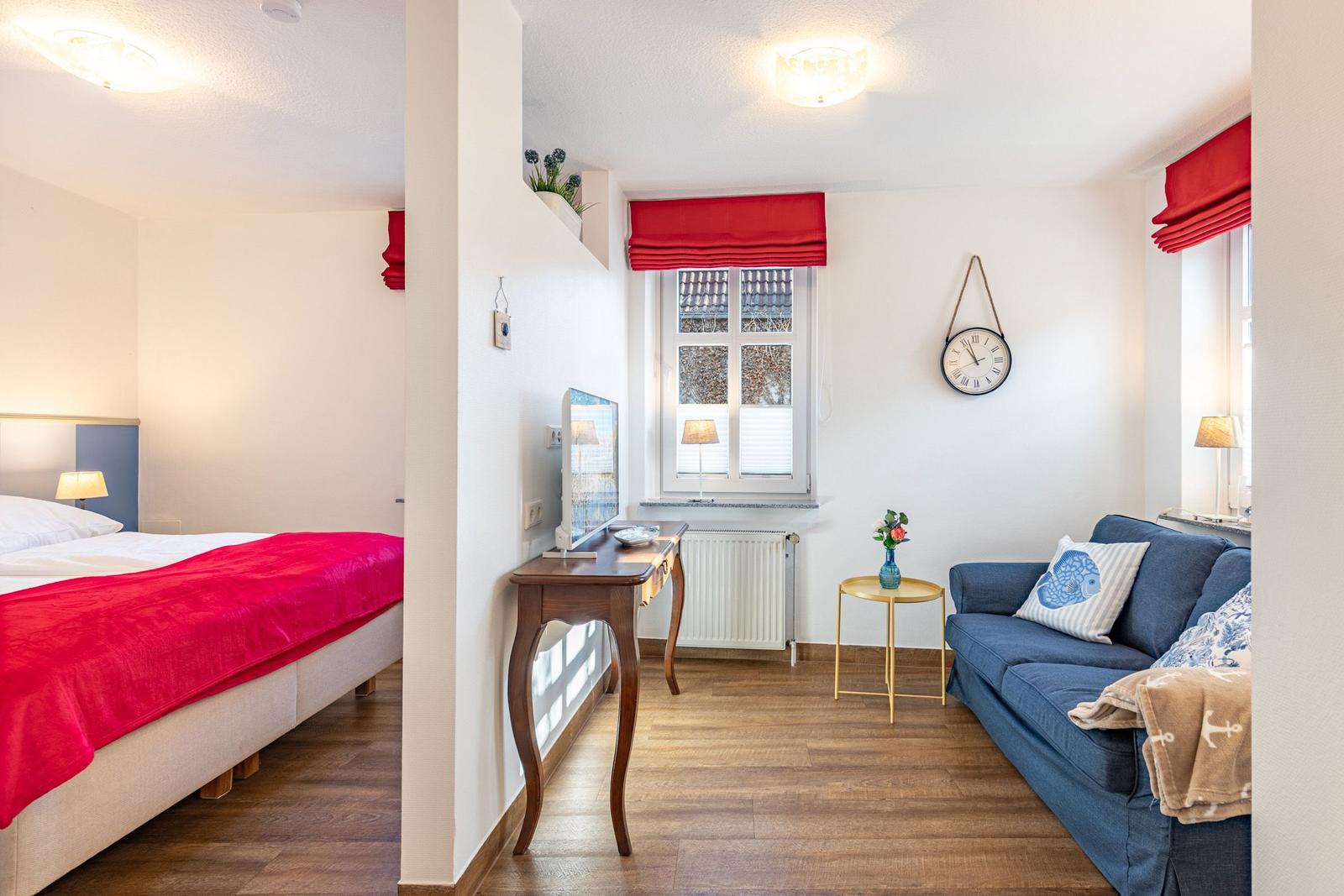 Schlafzimmer mit Bett und Wohnbereich mit Sofa und Fernseher.