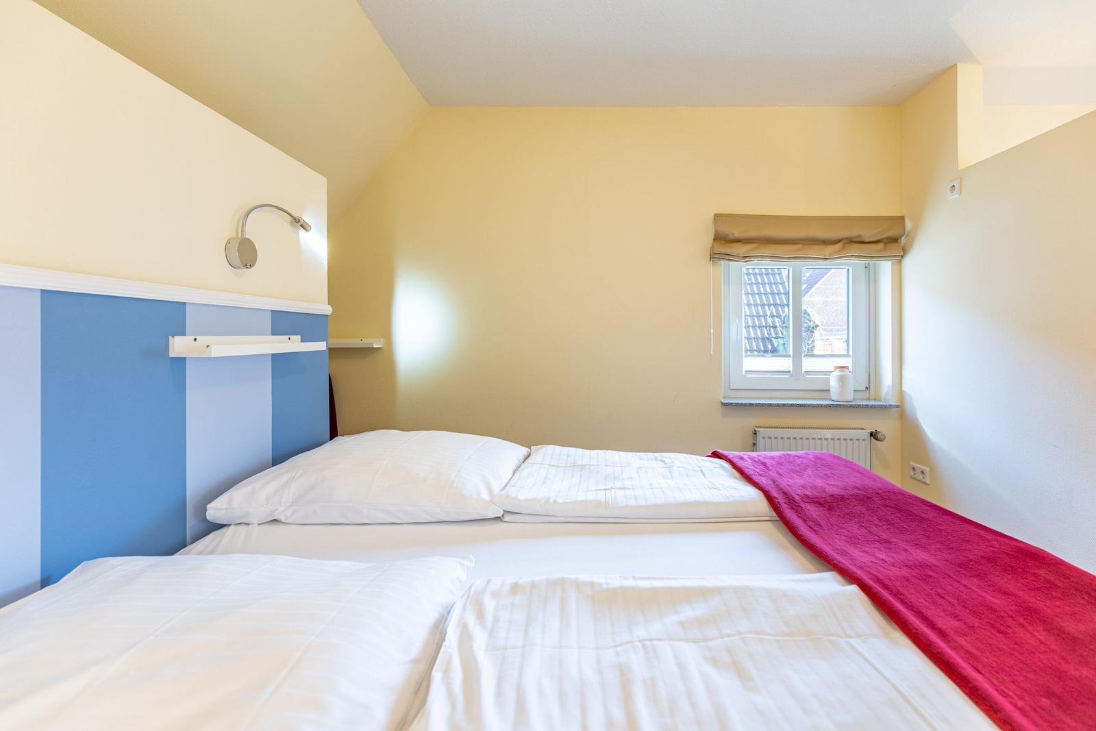 Schlafzimmer mit Bett, Fenster und Heizung.