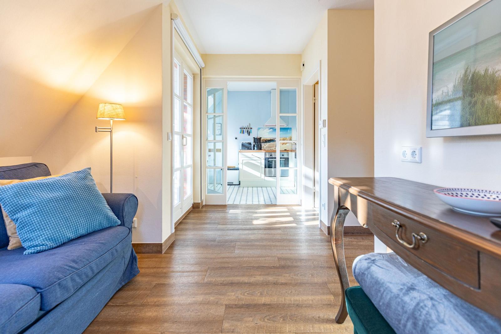 Wohnzimmer mit Sofa, Tisch und Blick in die Küche