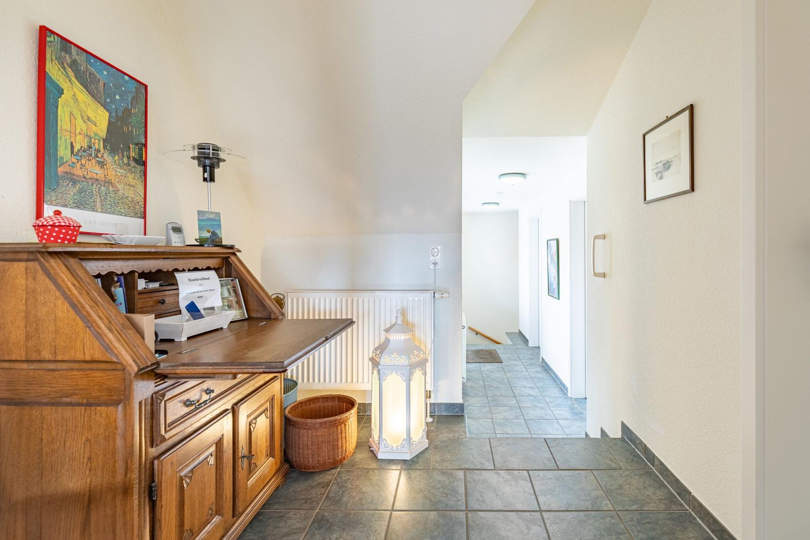 Hausflur mit Holzschrank, Wandbild und beleuchteter Laterne.