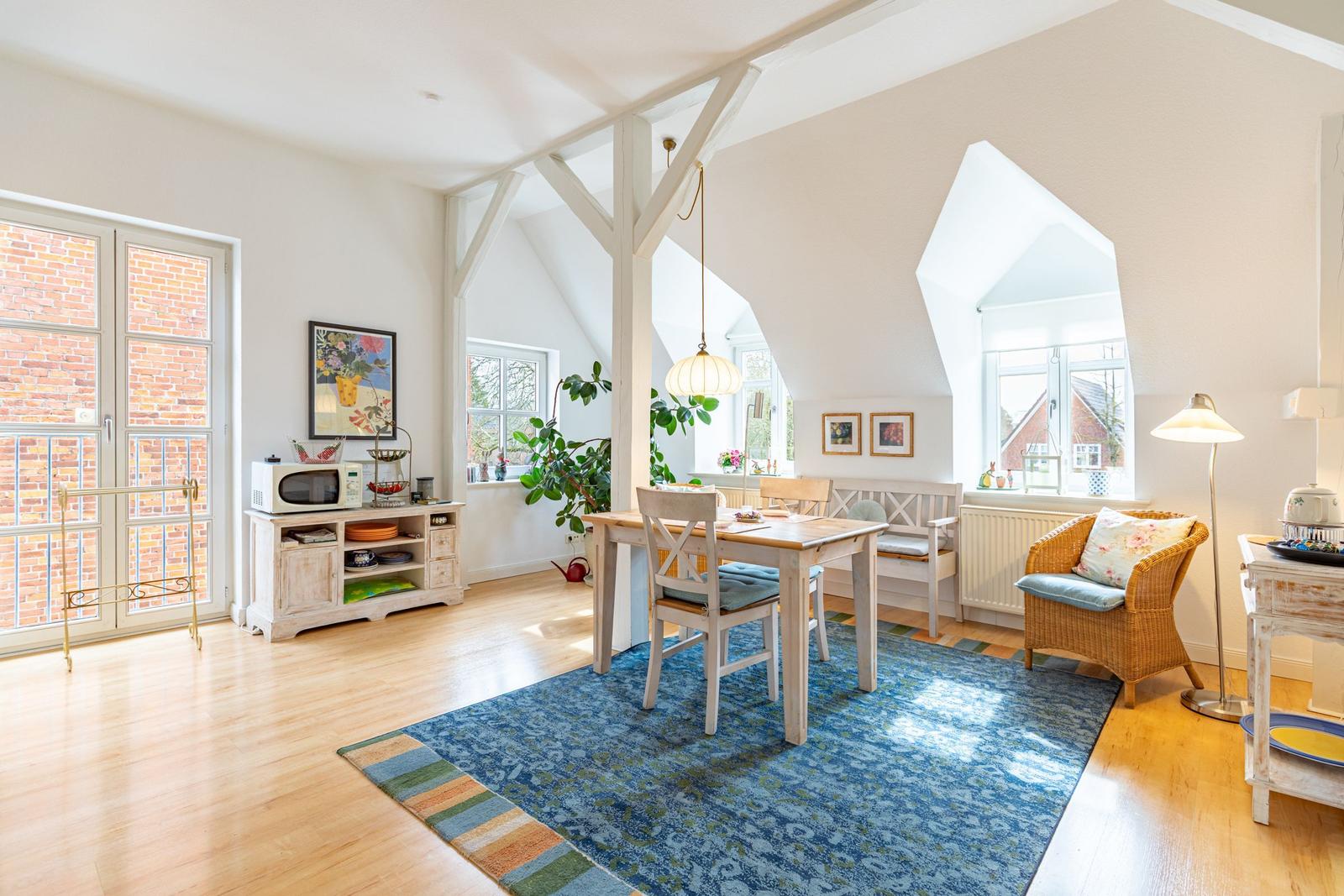 Ein Esszimmer mit Holzboden, Tisch, Stühlen und einem blauen Teppich.