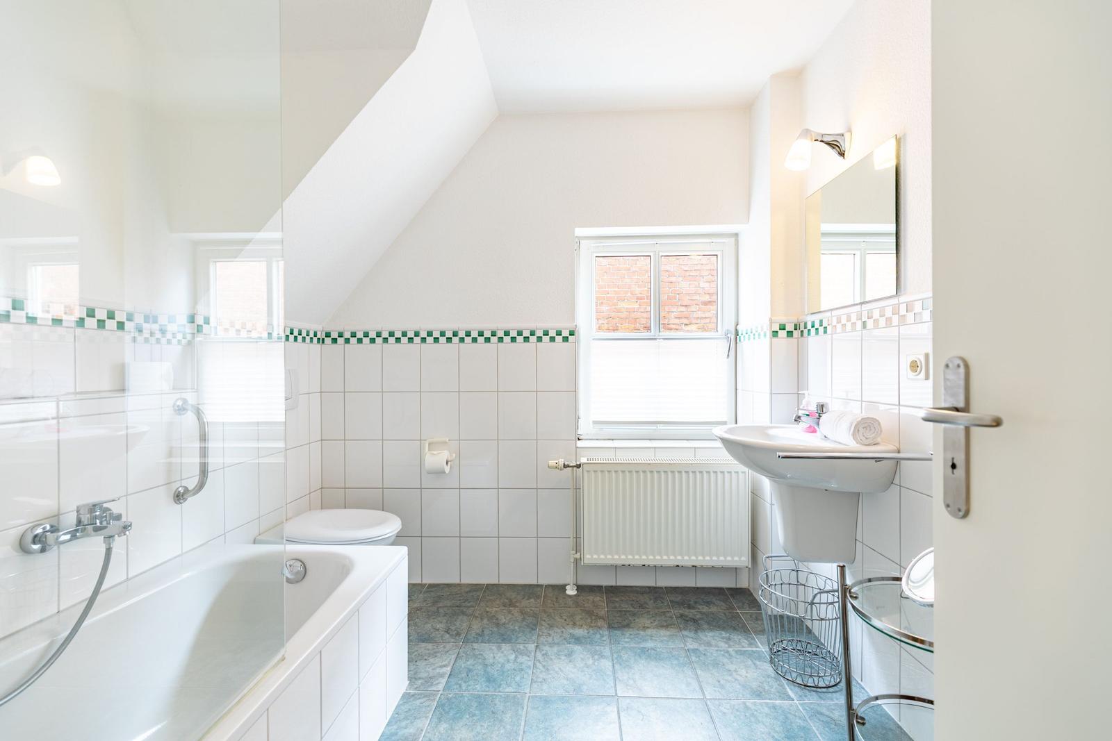 Badezimmer mit Badewanne, Toilette und Waschbecken unter Dachschräge.