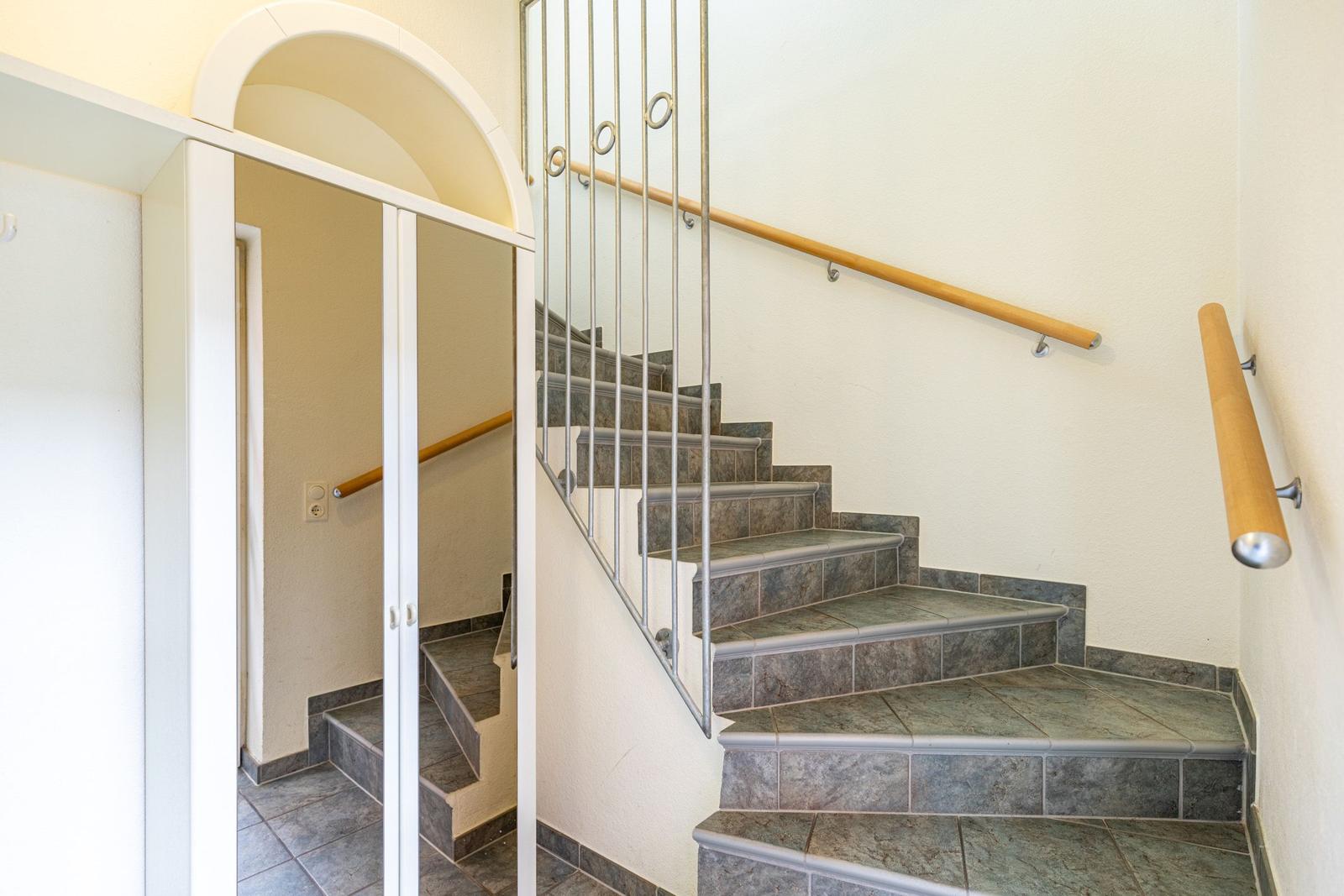 Treppe mit Steinbelag und Metallgeländer führt zur oberen Etage.