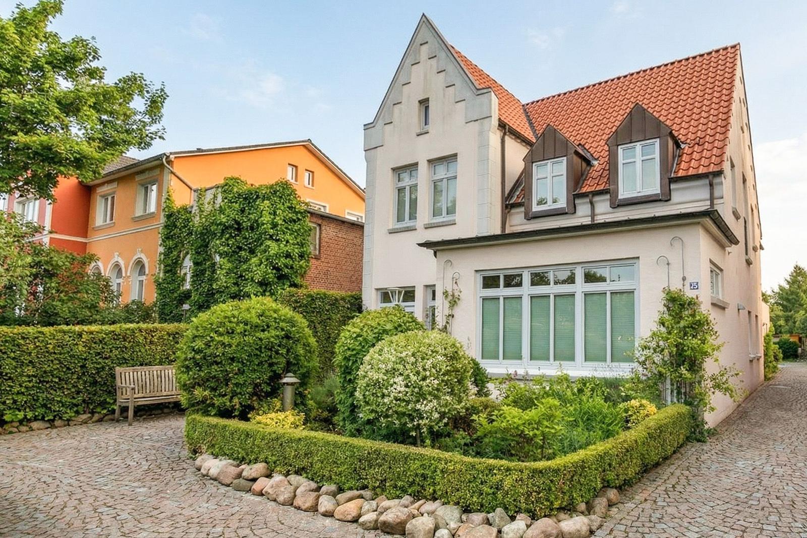 Haus mit rotem Dach, gepflegtem Garten und Kiesweg.