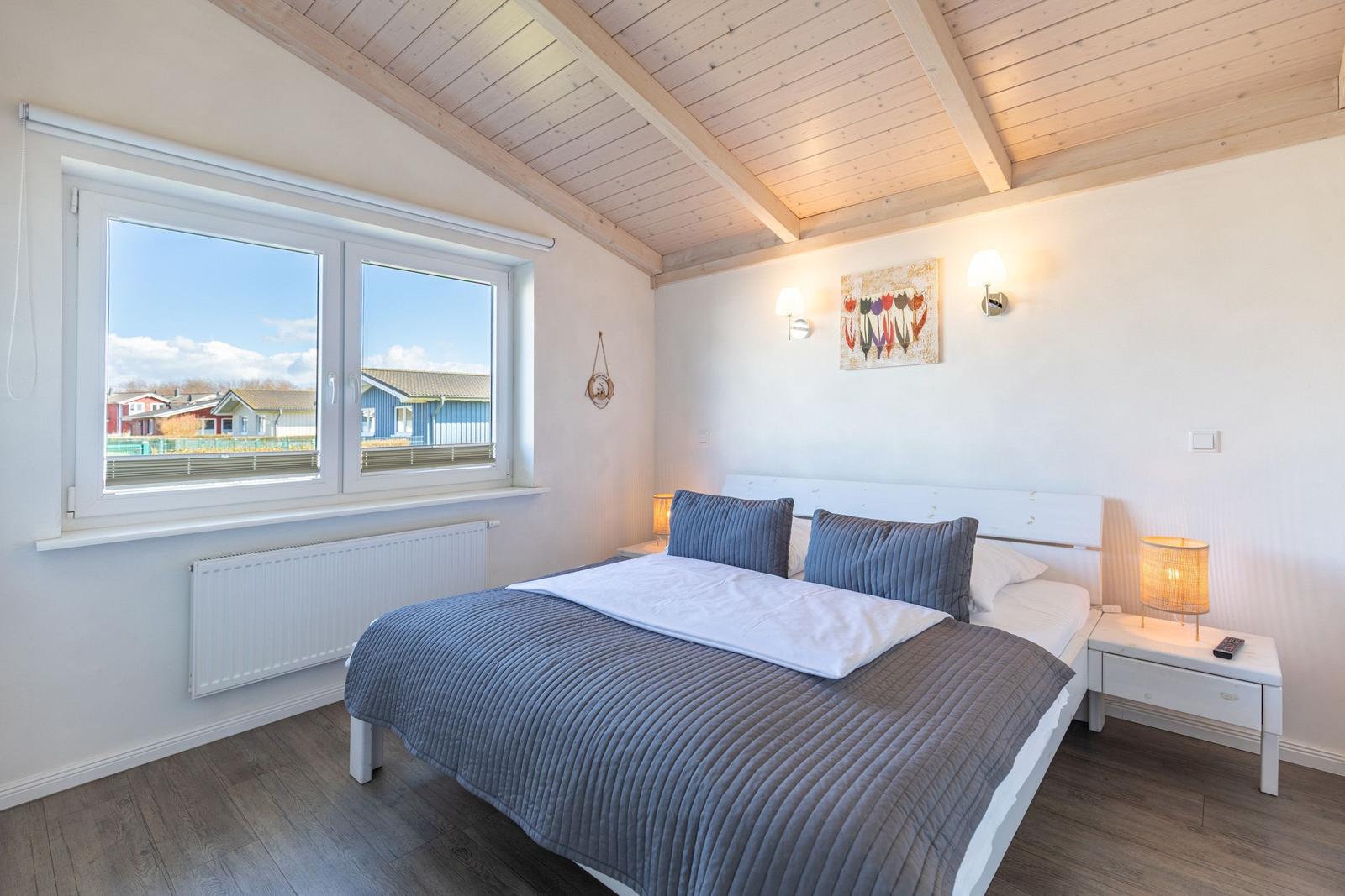 Schlafzimmer mit Doppelbett, Fensterblick und Holzdecke.