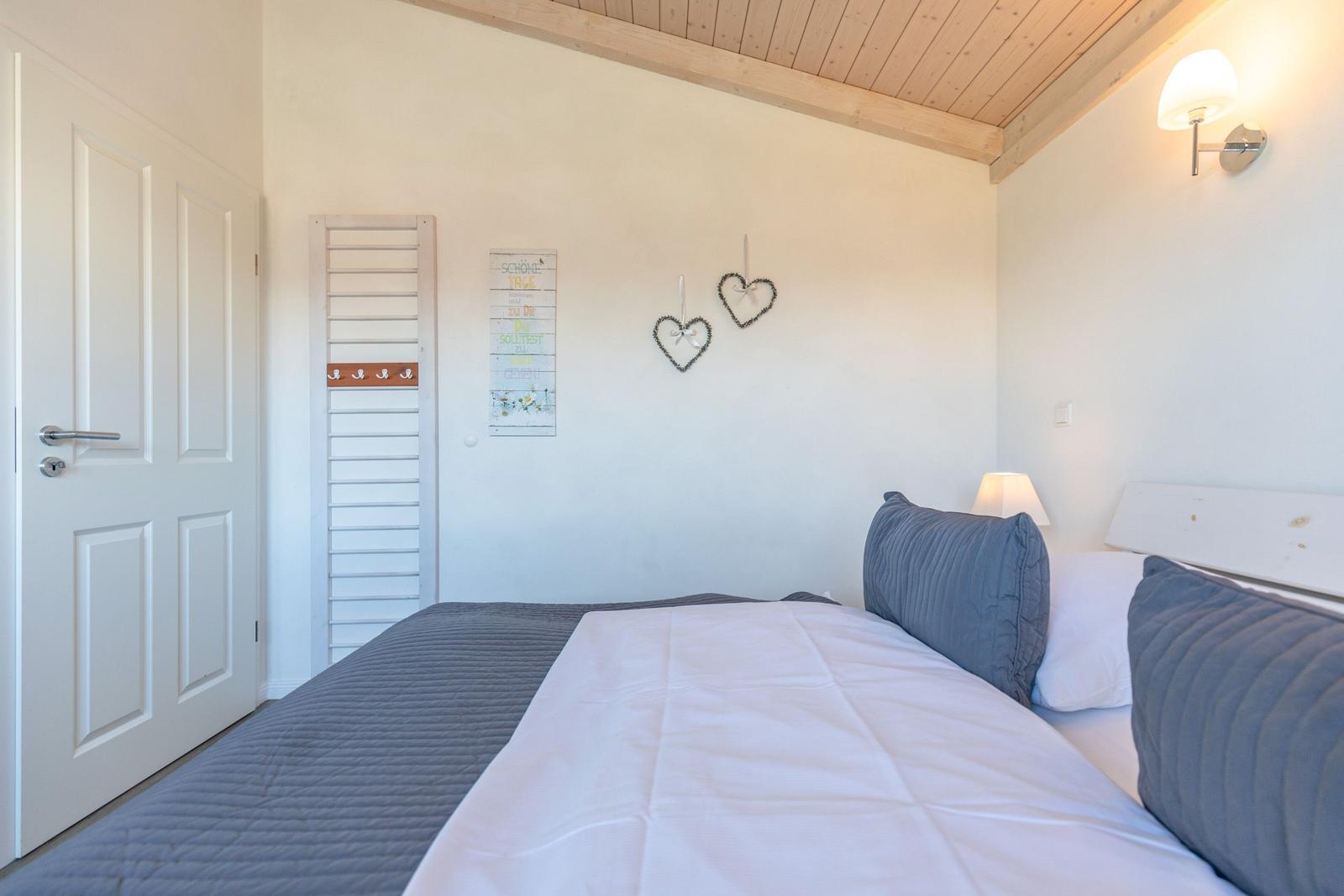 Schlafzimmer mit Bett, Wanddekoration und Holzdecke.