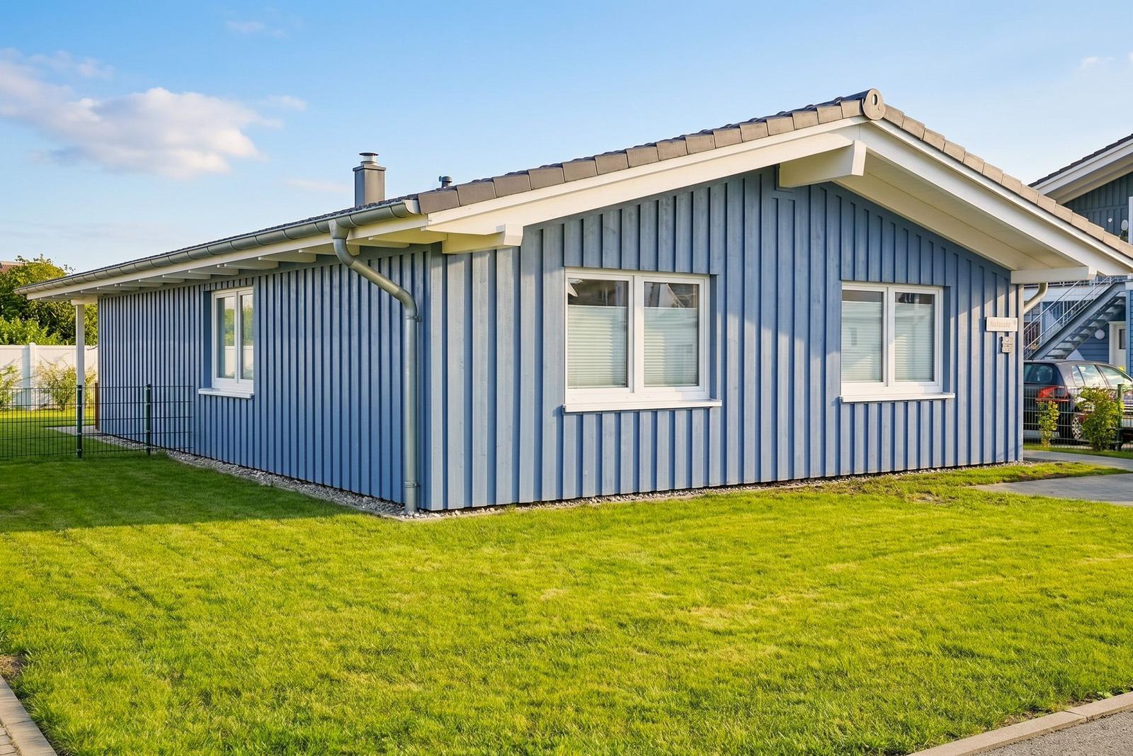 Blau gestrichenes Haus mit grünem Rasen und weißen Fenstern.