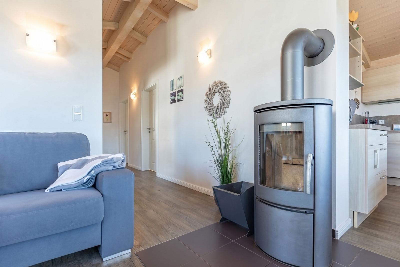 Wohnzimmer mit Sofa, Kaminofen und Holzboden